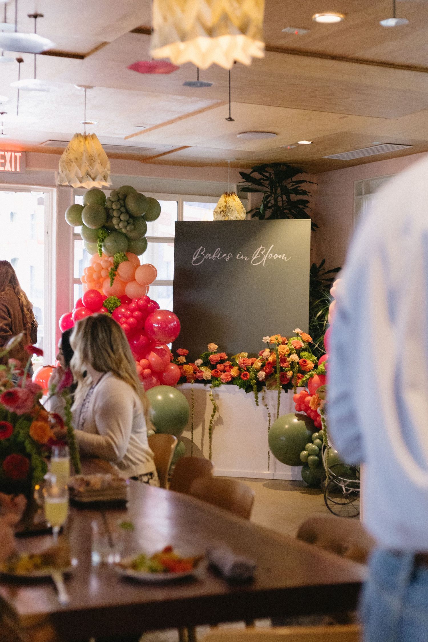 Babies in Bloom baby shower with colorful balloon arch, floral arrangements, and dark welcome sign in decorated venue.