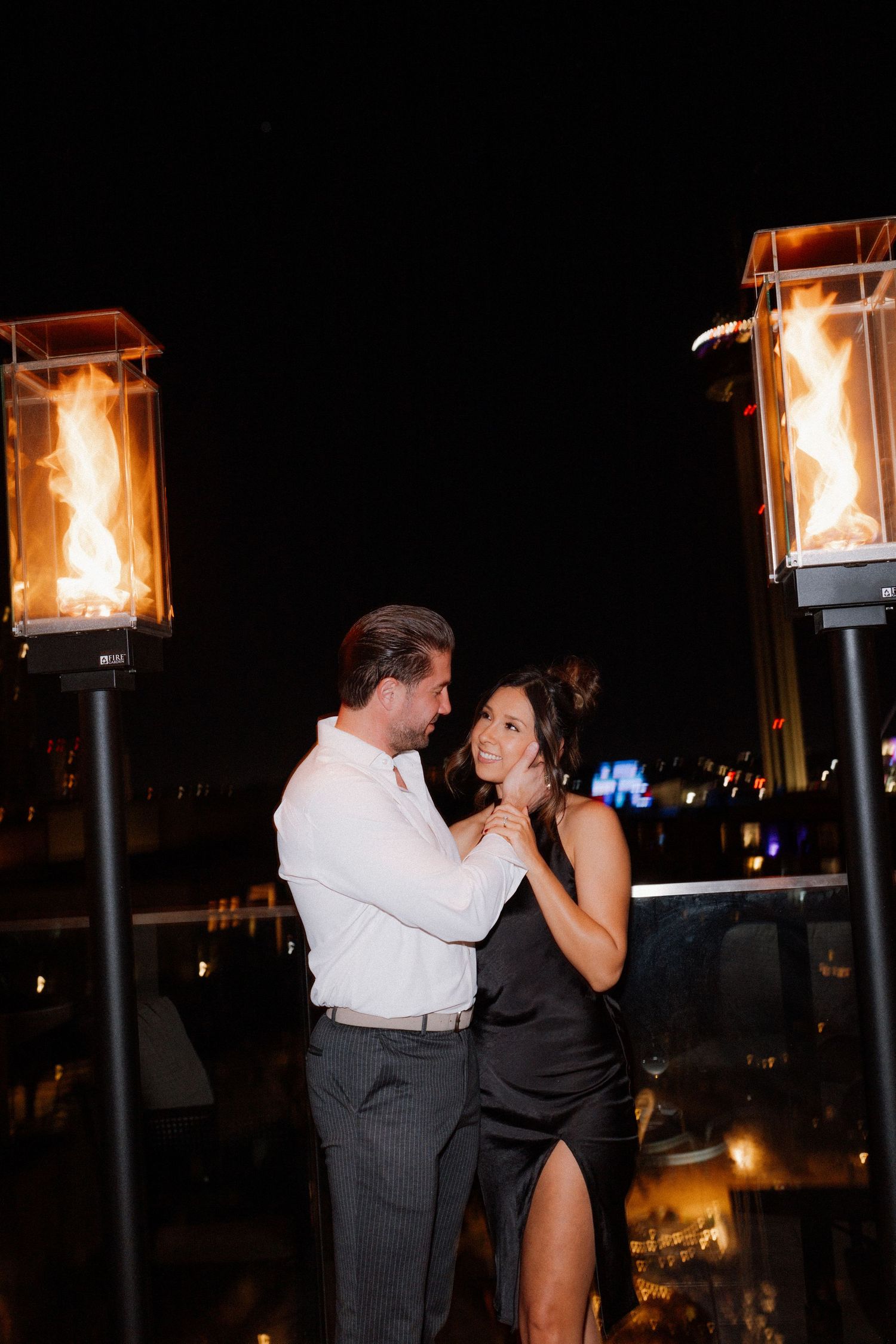 Romantic evening scene with couple dancing near outdoor flame lanterns.