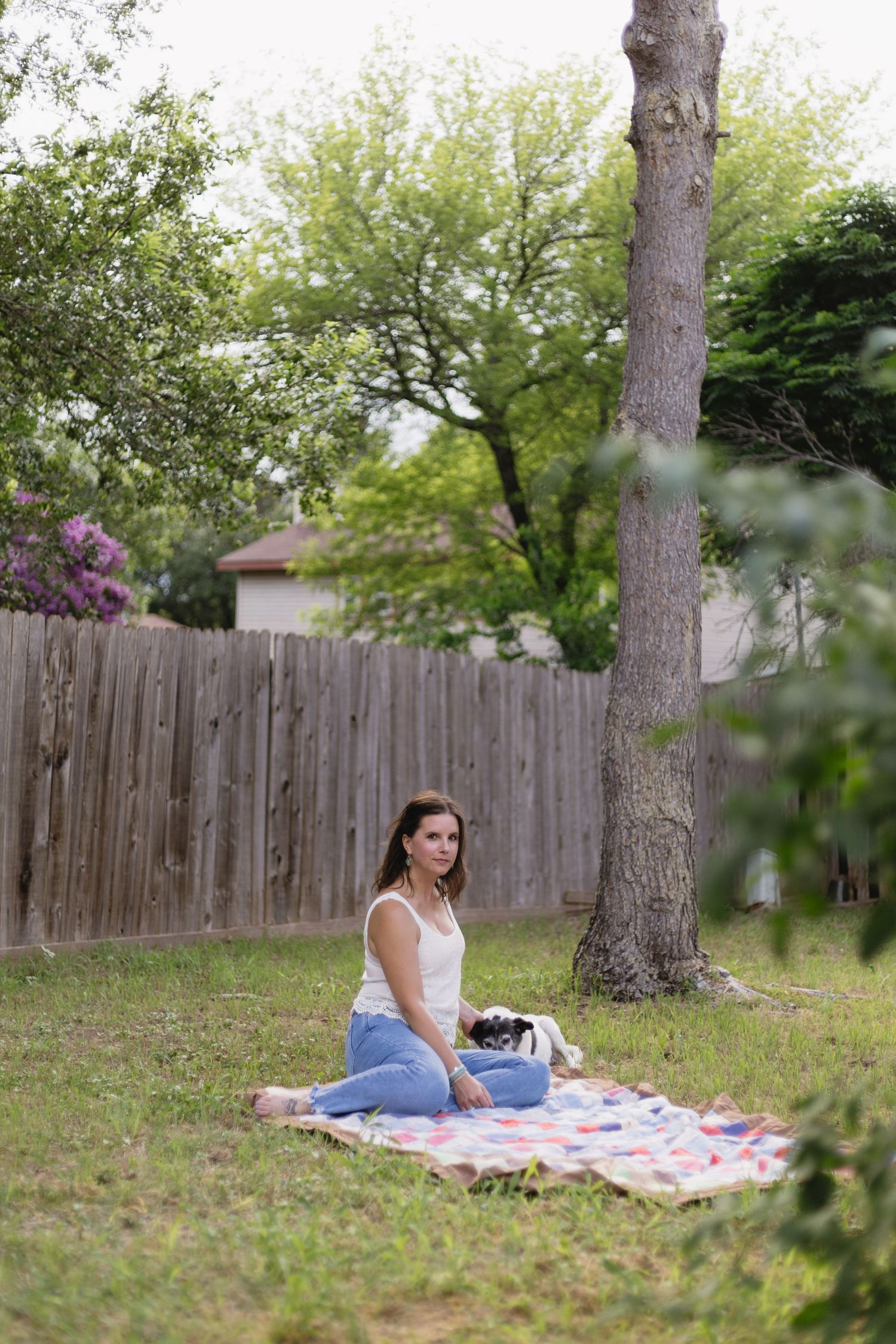 A relaxing afternoon picnic scene with a blanket spread under a tree in a backyard.