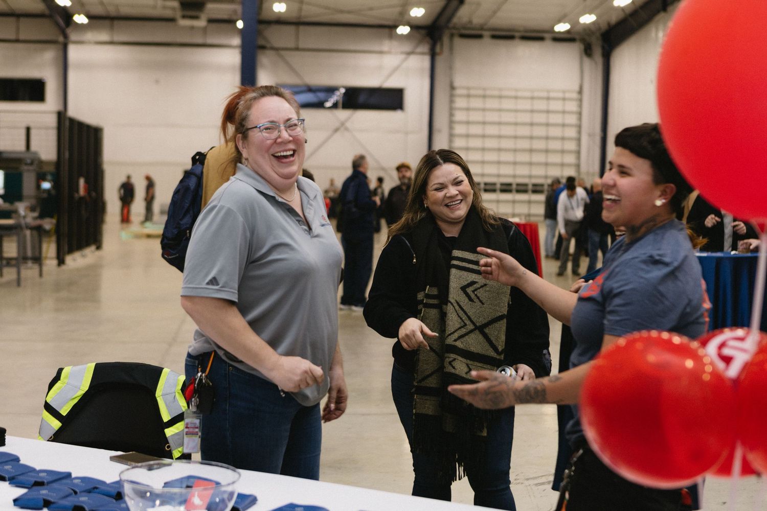 Students gather at tables during a career fair event in a large indoor space with red balloons and banners.