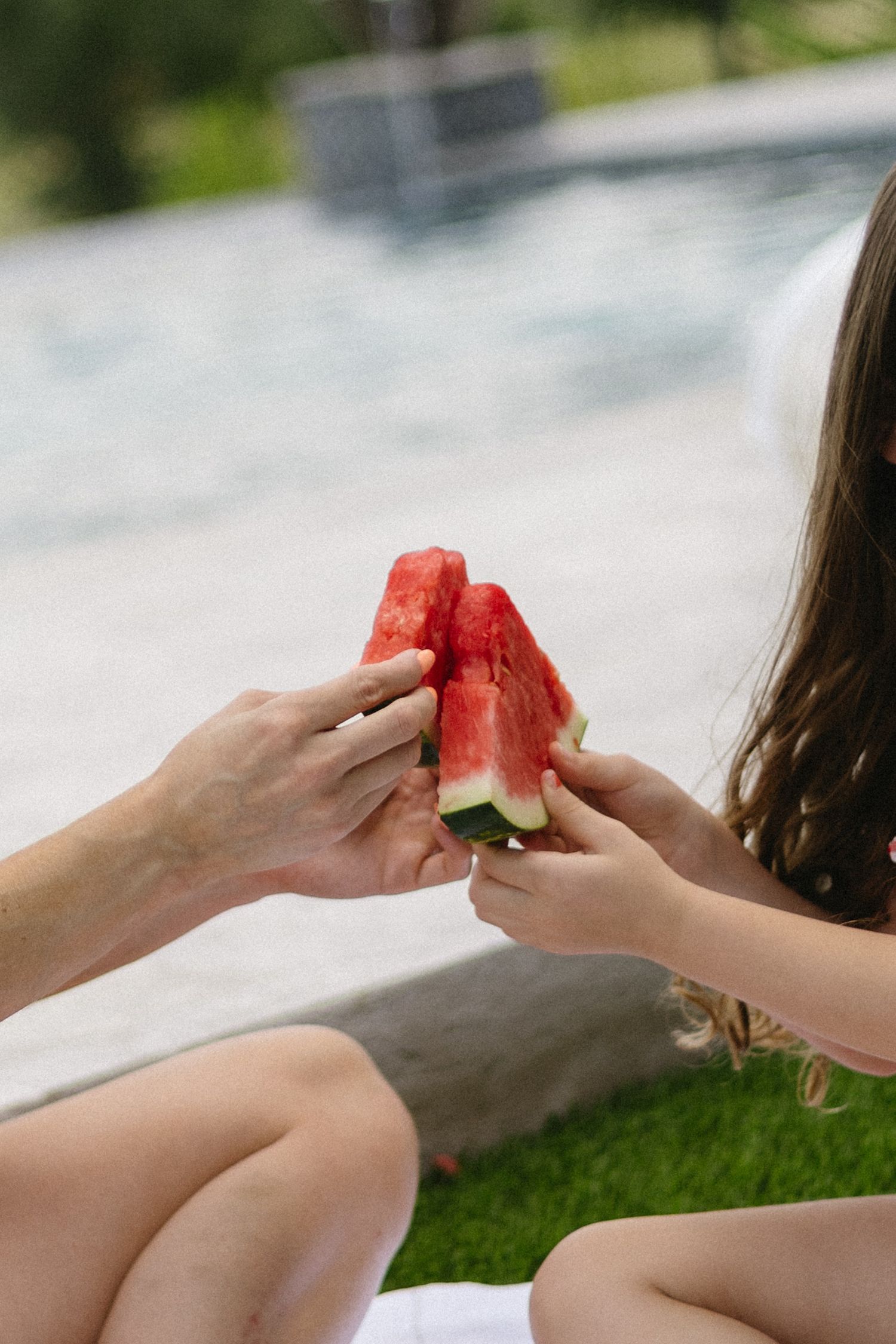 Two people sharing a slice of fresh red watermelon on a summer day outdoors.