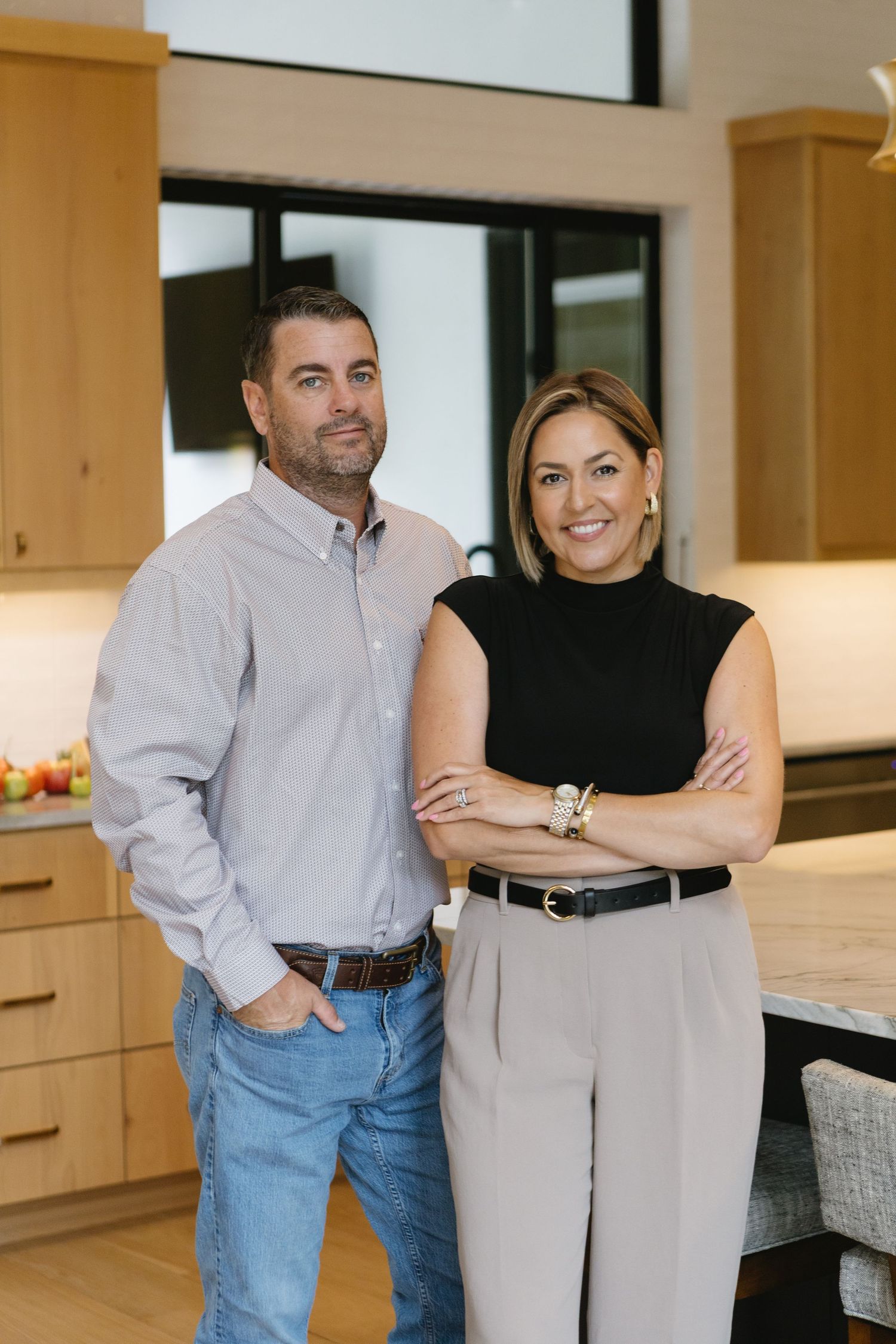 Professional couple posing together in contemporary kitchen setting.