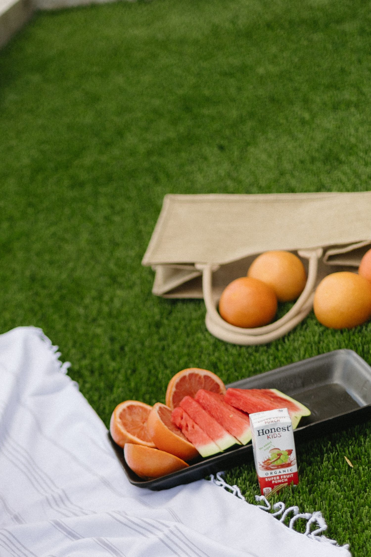 Fresh eggs and sliced grapefruit arranged on a white napkin against green grass for a healthy outdoor breakfast setting.