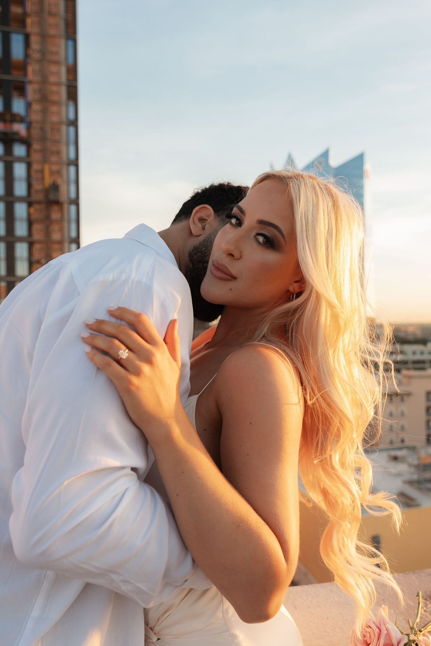 A romantic embrace captured during sunset on a city rooftop.