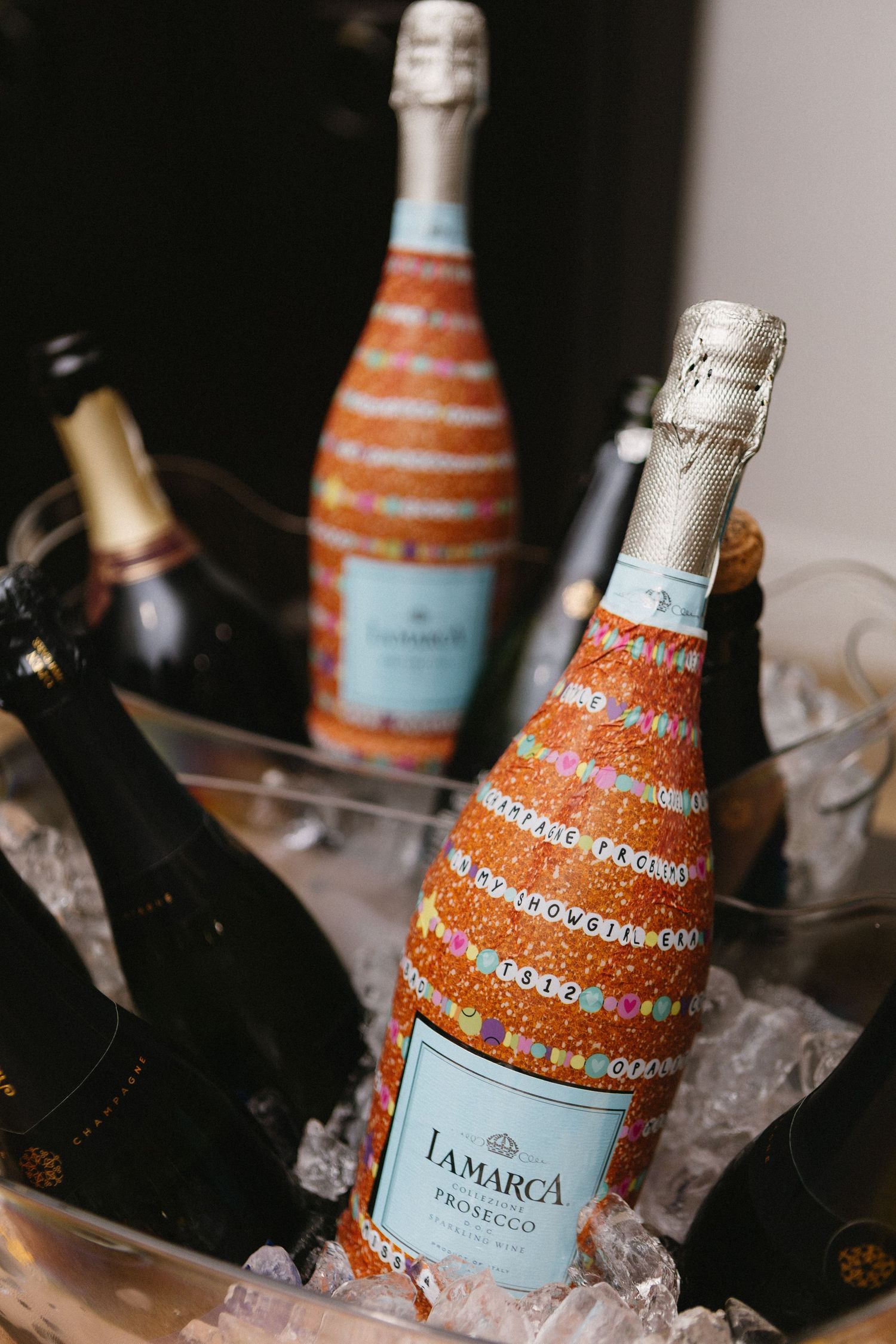 La Marca Prosecco bottle decorated with colorful beaded jewelry chilling in ice bucket at a celebration party.