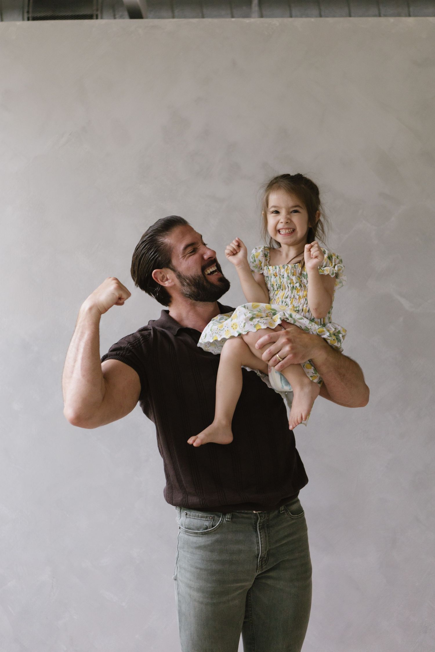 A joyful moment captured between two people showing excited expressions against a concrete wall.