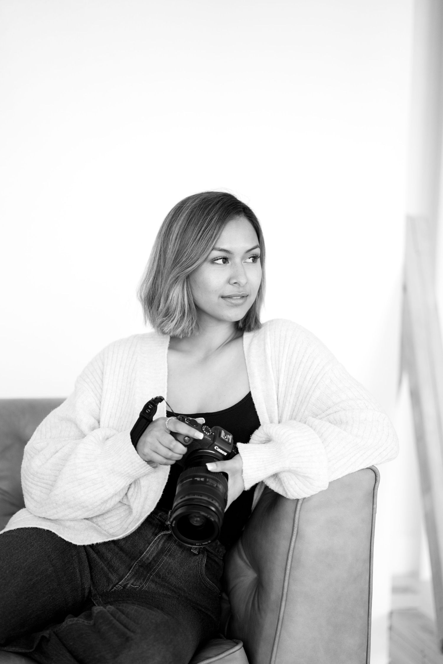 Black and white portrait series showing a photographer with a camera sitting on a couch in different poses.
