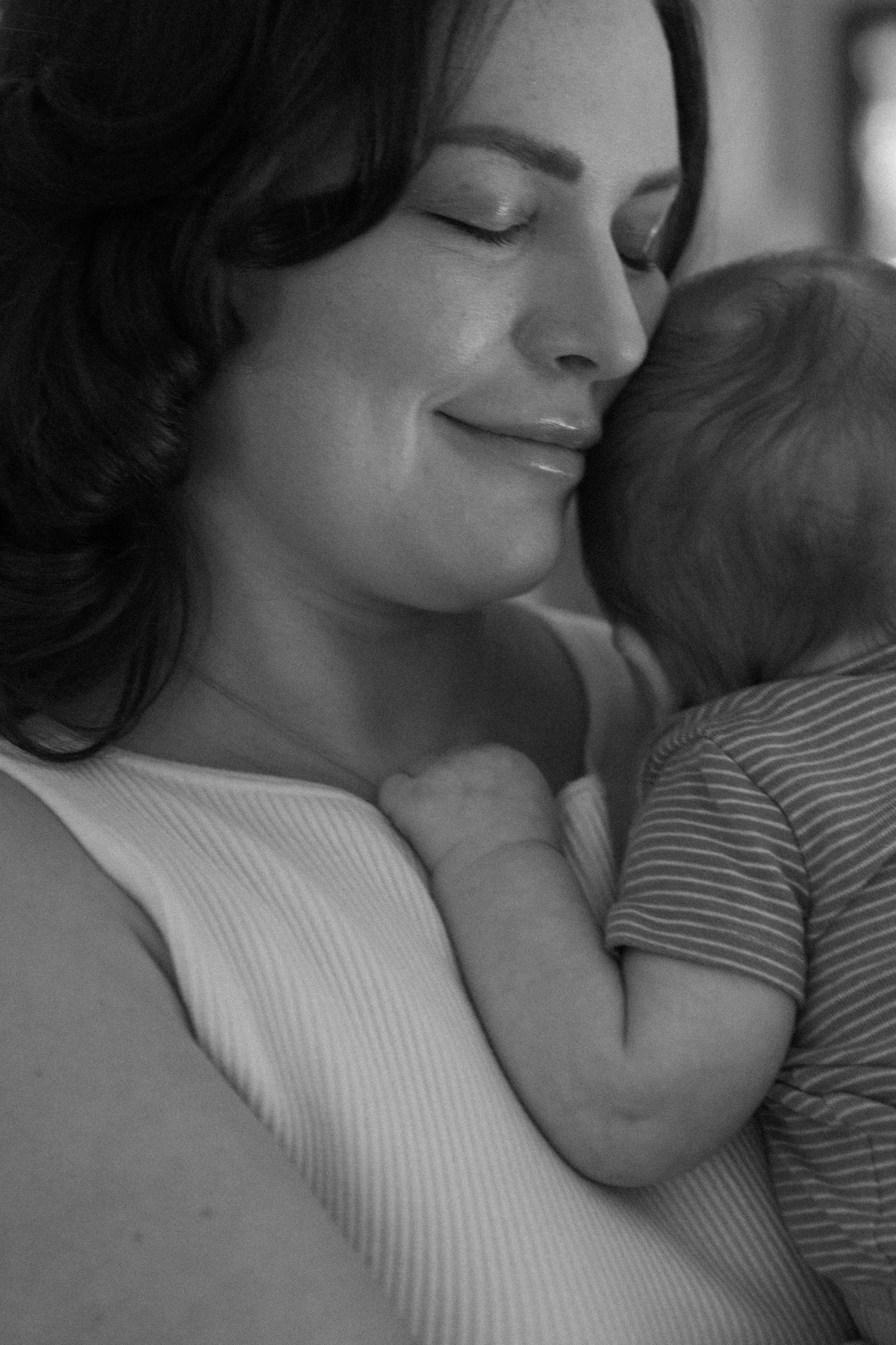 A tender black and white portrait of a mother and baby in an intimate embrace, sharing a peaceful moment together.