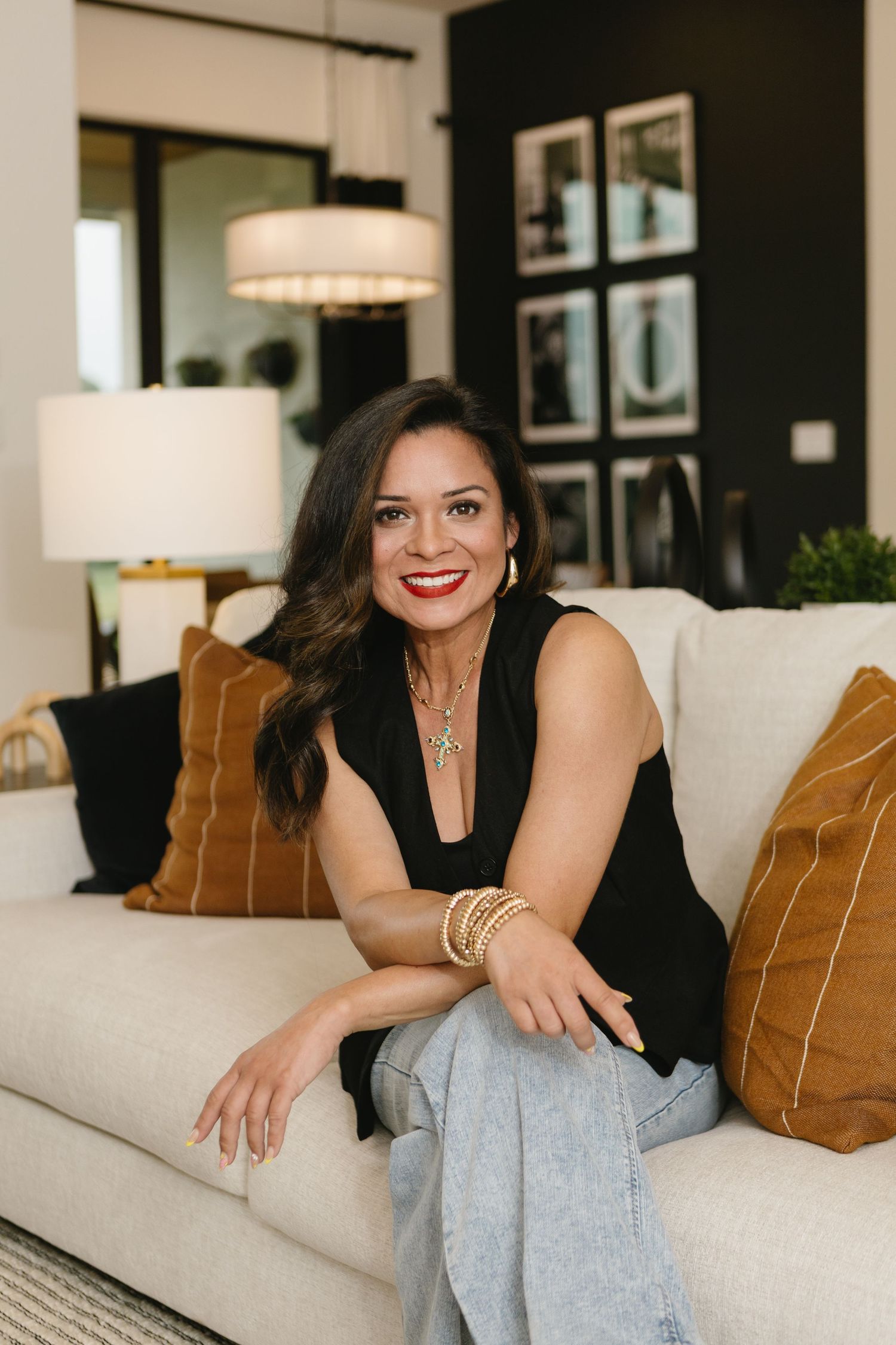 Person in black top sitting casually on cream couch with brown pillows.