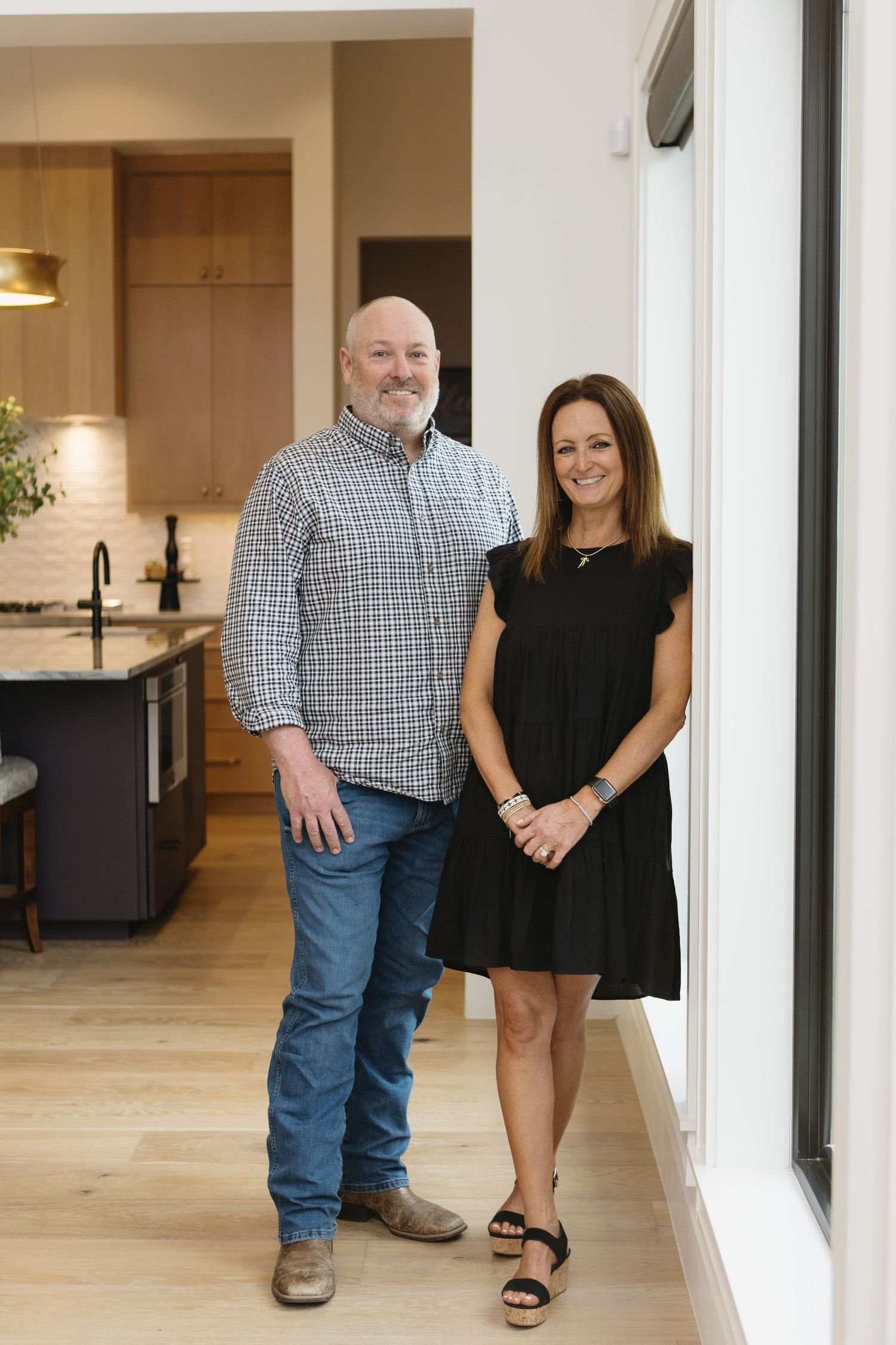 Two people walking together in a modern hallway with light wood floors and white walls.