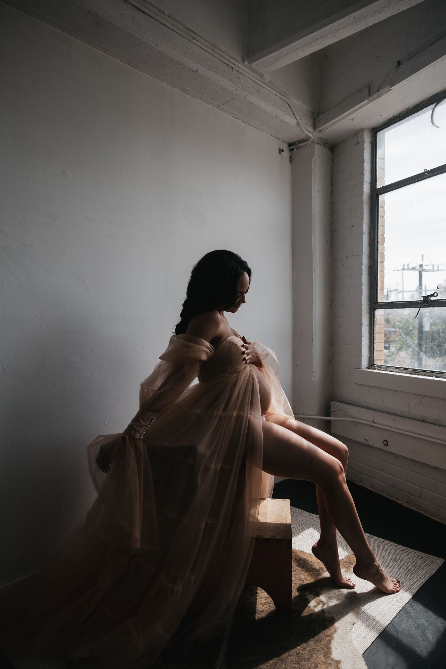 A person sits in deep contemplation by a window in a sparse room, creating a moody atmospheric scene.