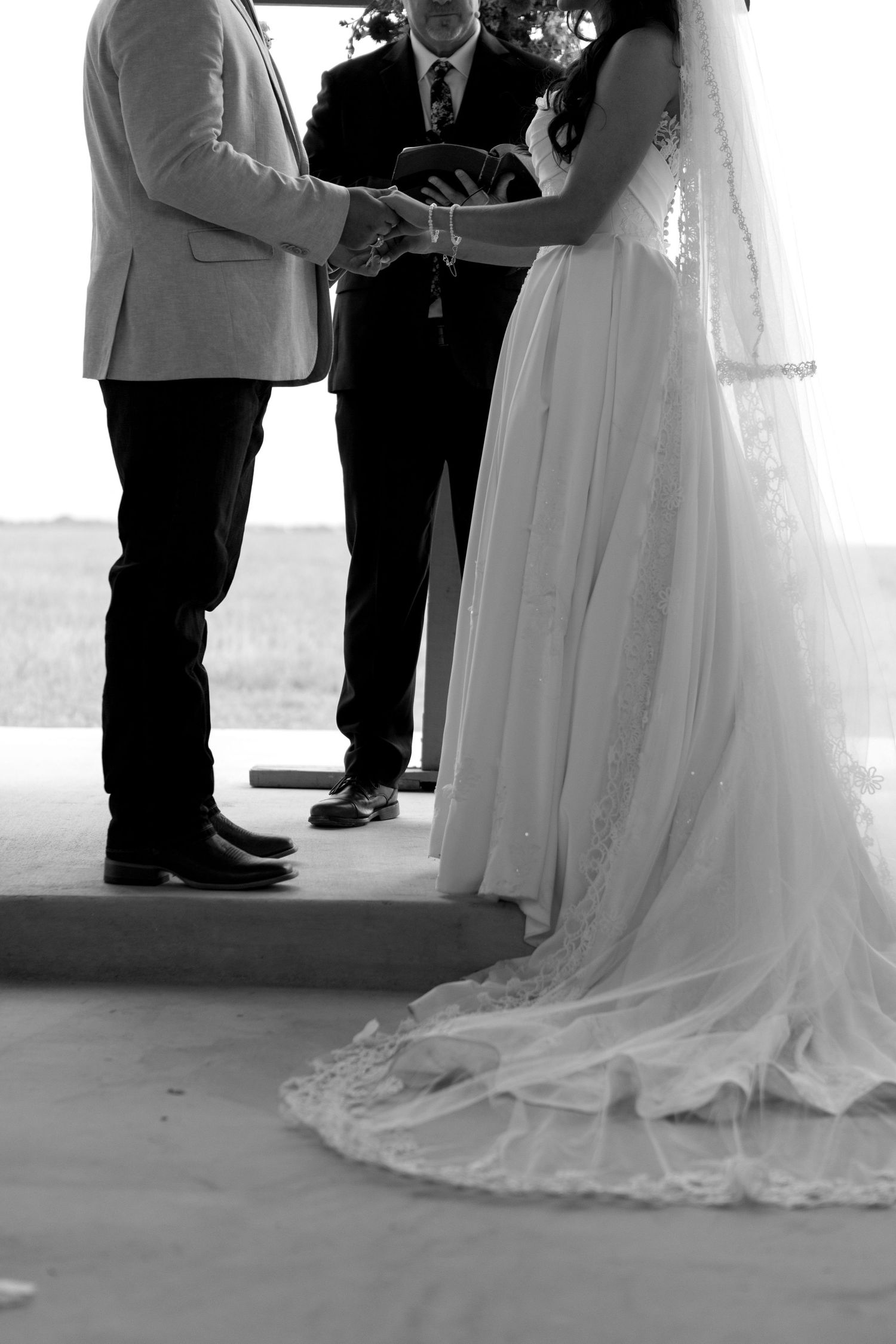 Black and white photo of bride and groom exchanging vows at wedding ceremony.