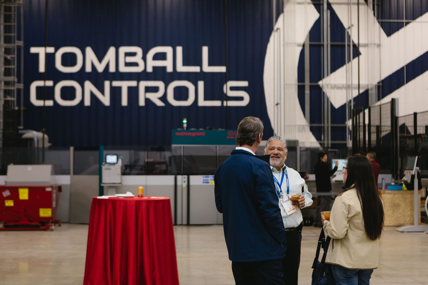 Business professionals have a conversation near the Tomball Controls signage at an industrial facility.