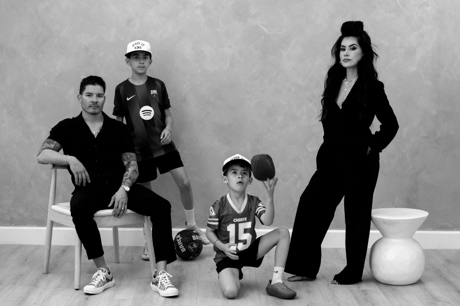 Black and white family portrait with two adults and two children posing in a modern studio setting.