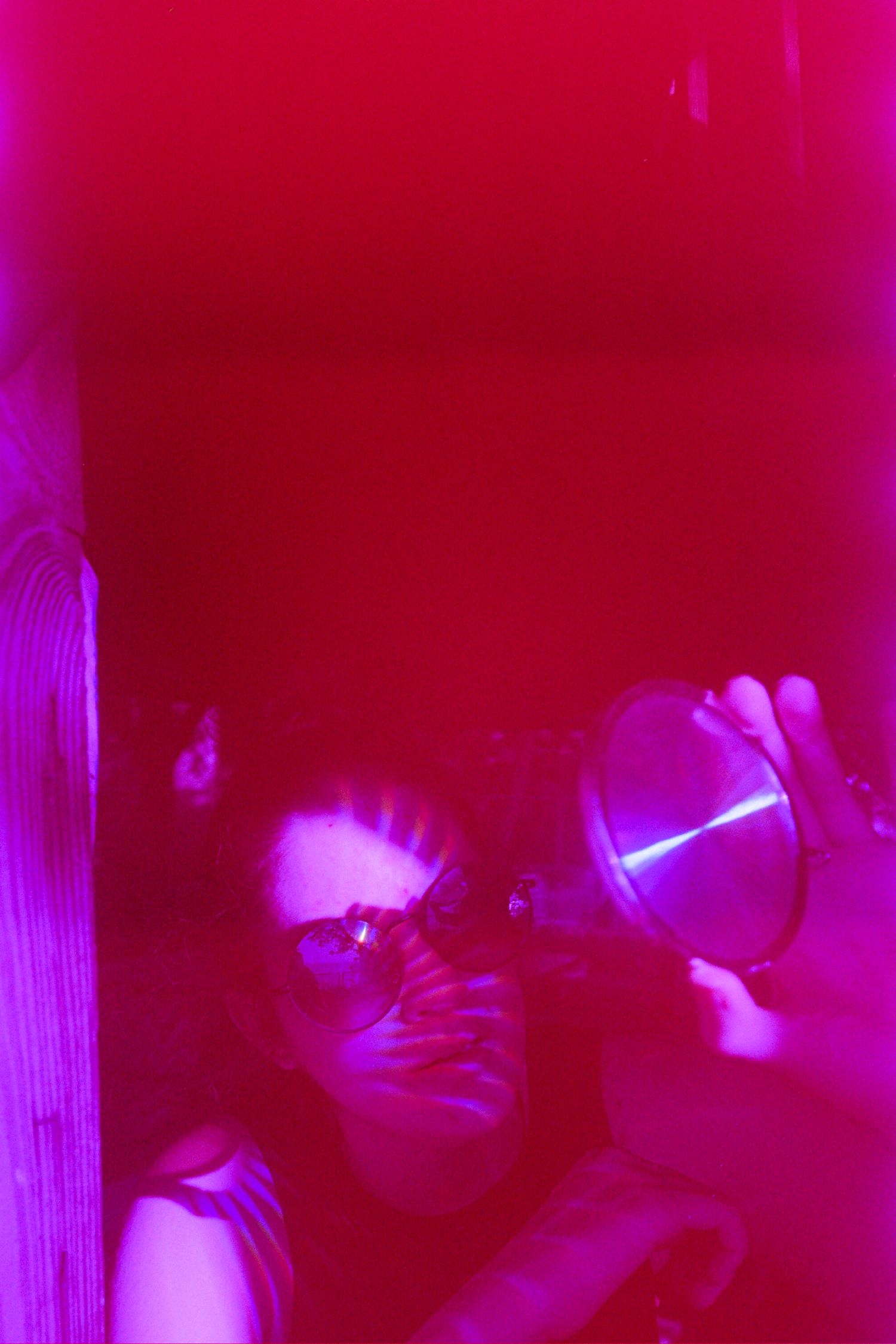 A woman holding a sunglass up to her face.