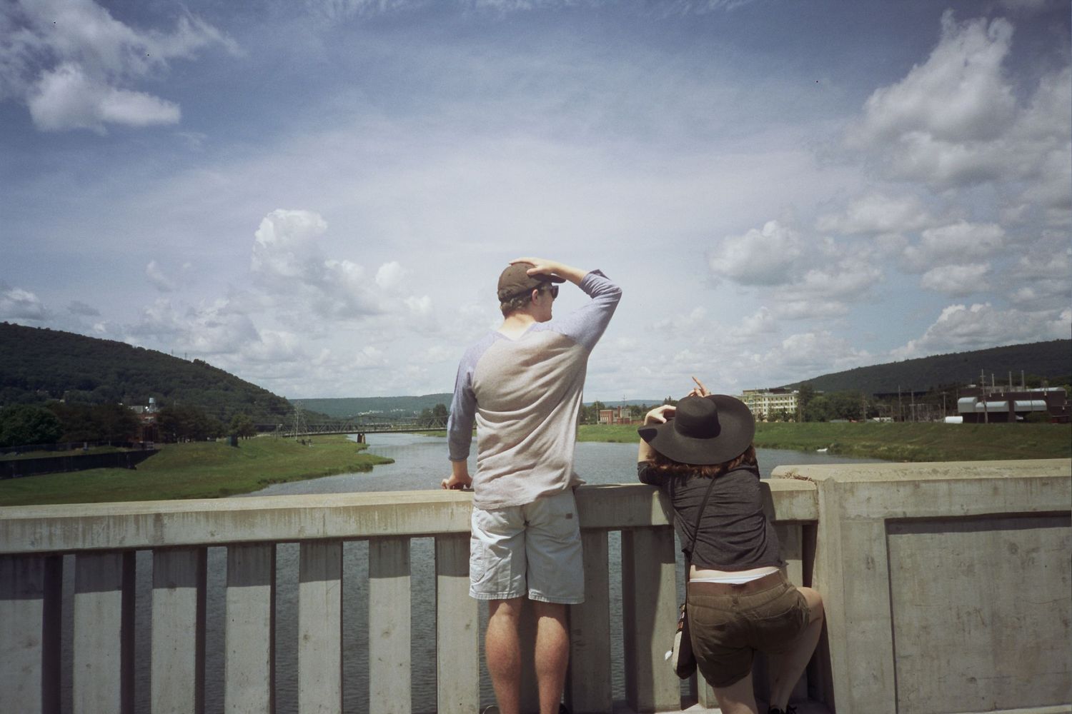 Two people looking at the sky over a bridge.