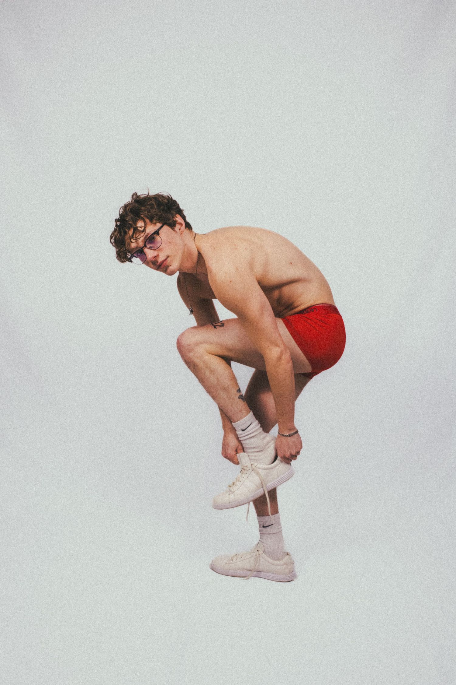 A man tying his shoe in front of a white background