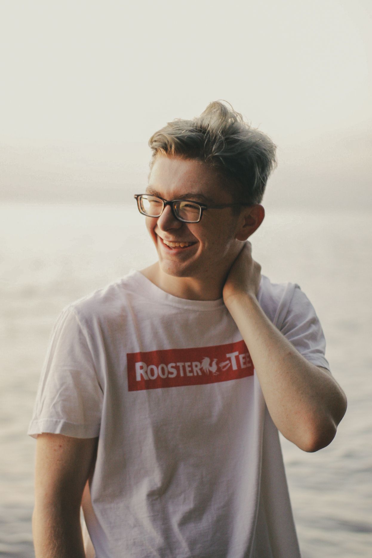A man laughing in front of a lake.