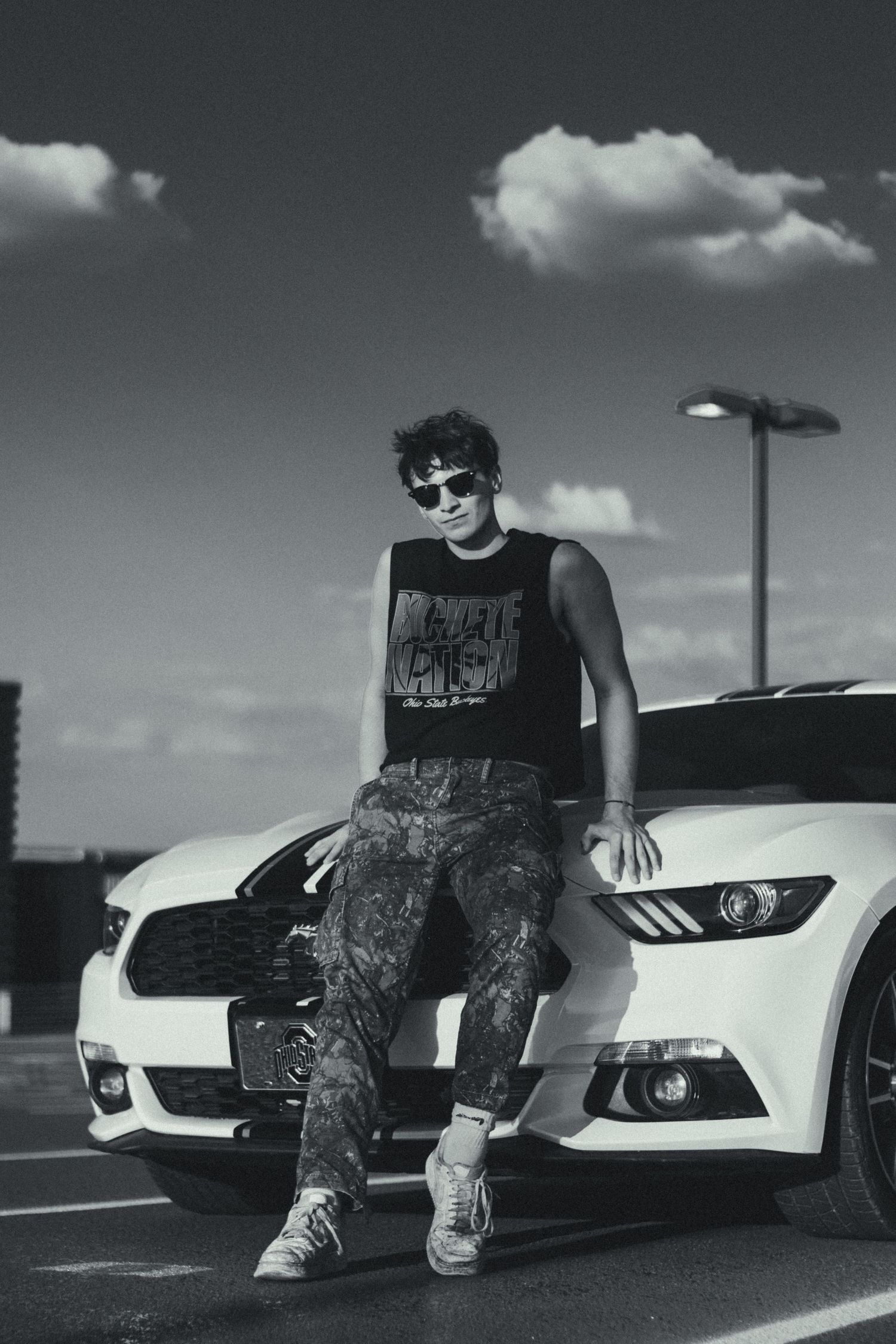 A man with sunglasses leaning on his car.