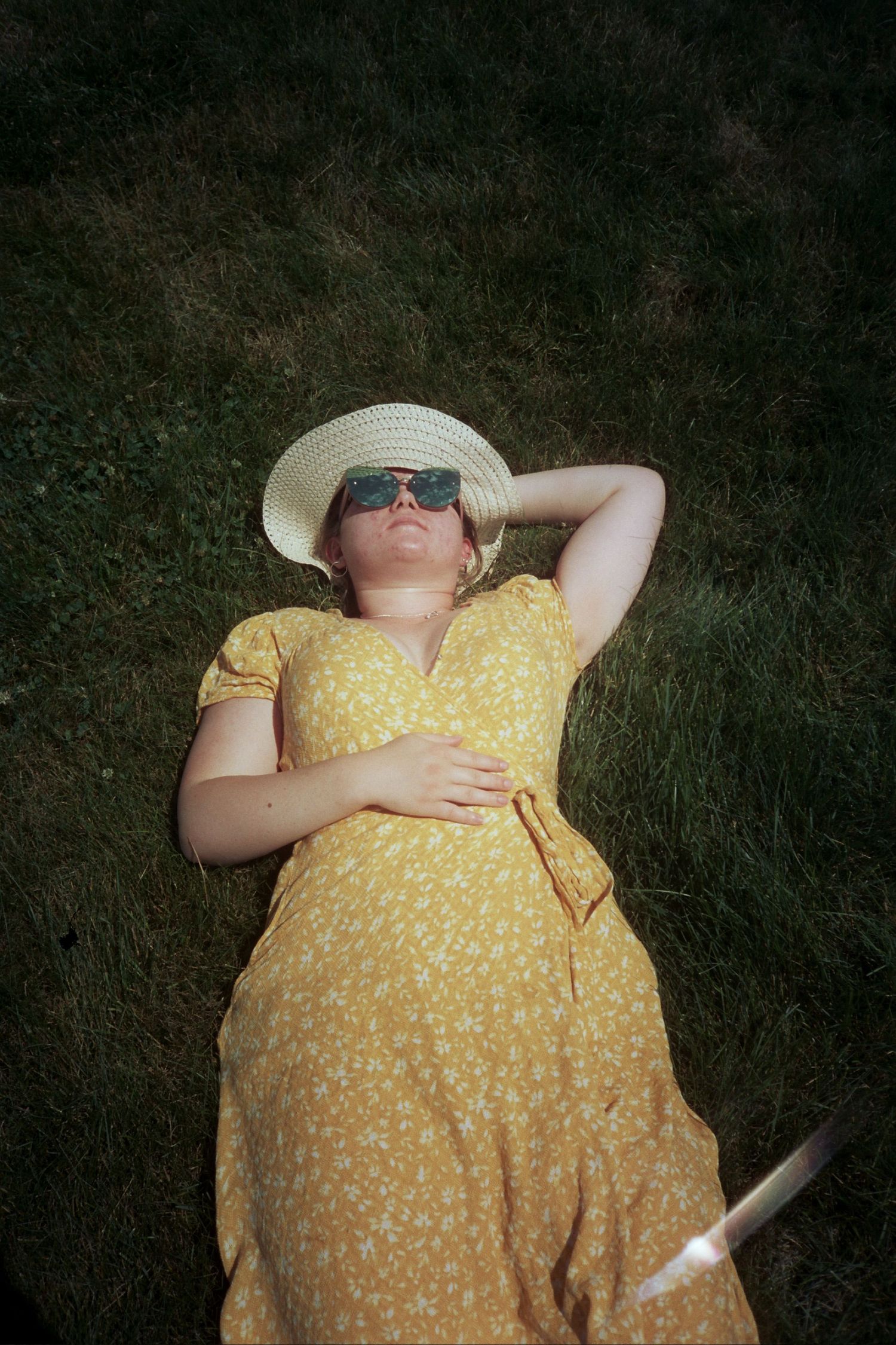 A woman in a yellow dress laying on green grass