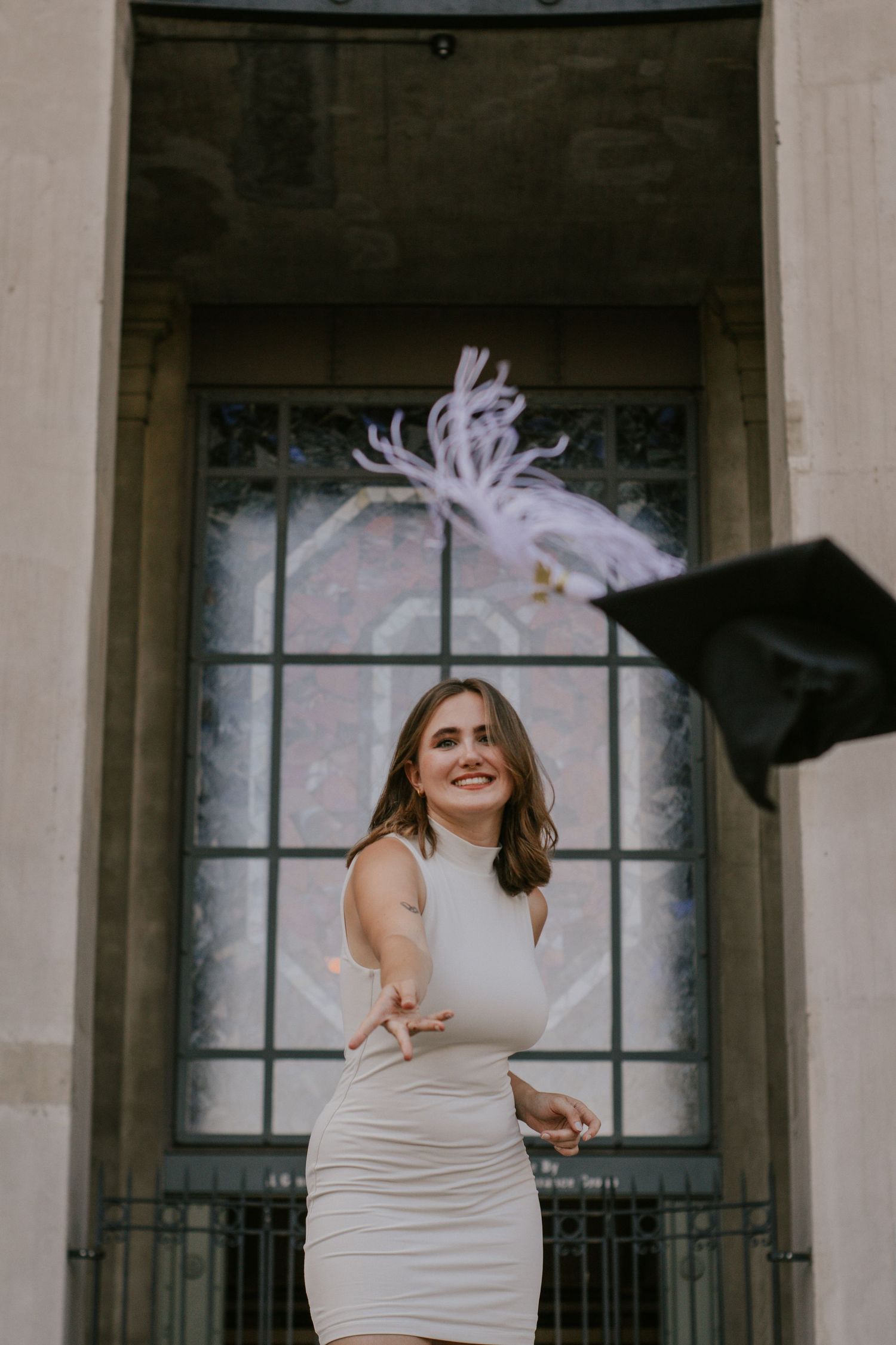 A woman tossing her cap towards the camera