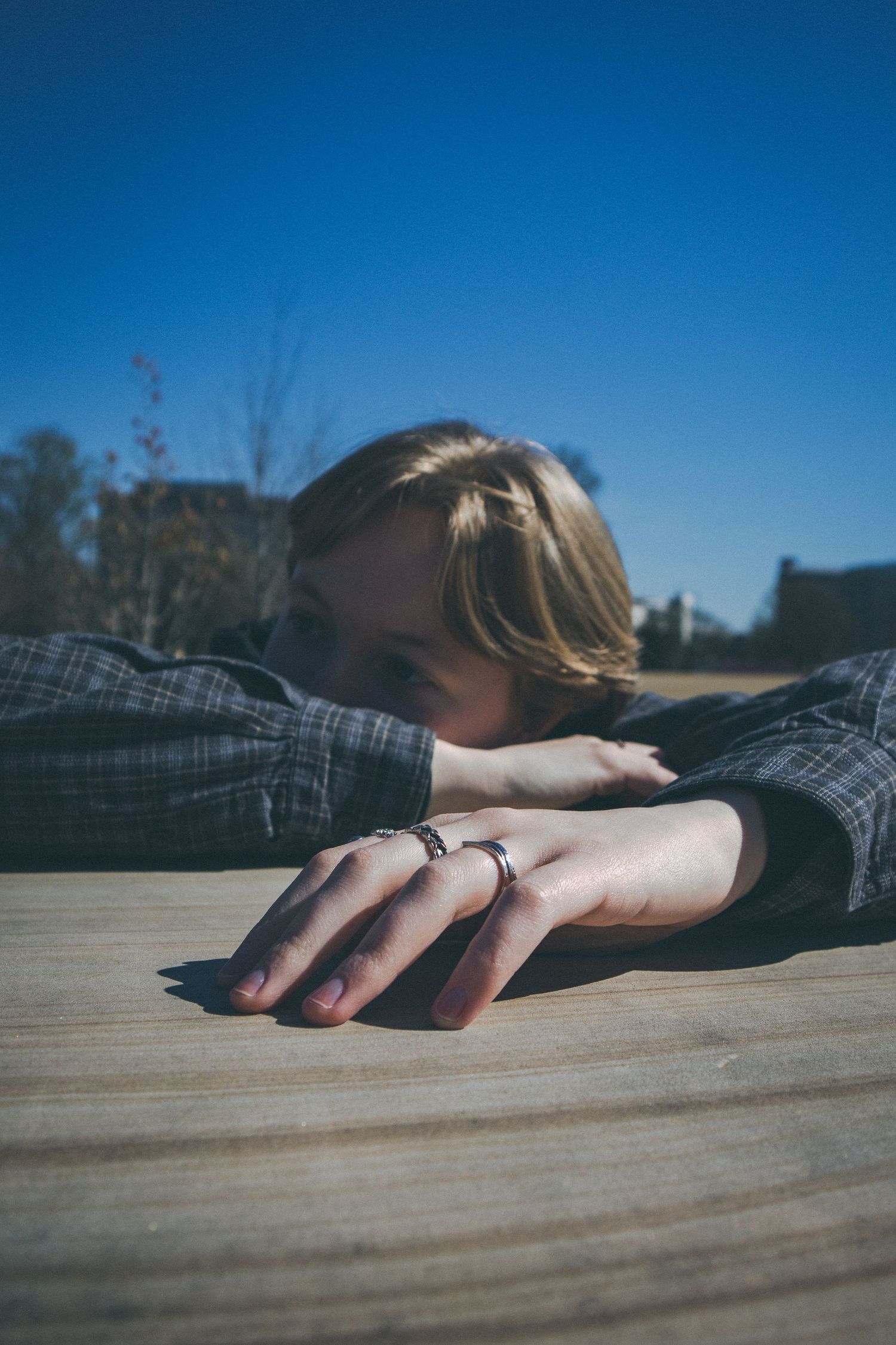 A person with their head on their hands in front of a blue sky.