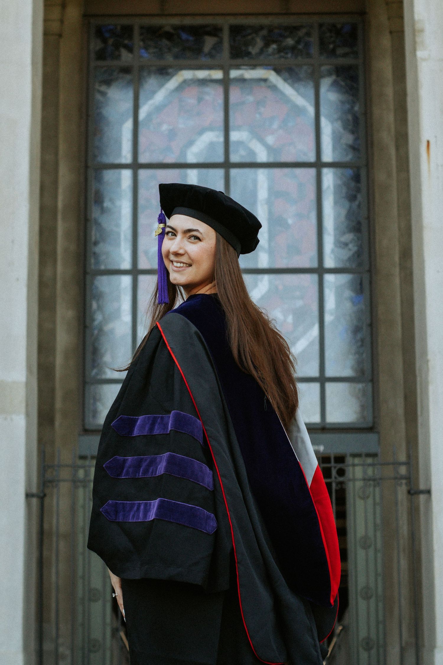 A woman looking back to the camera in her graduation regalia.