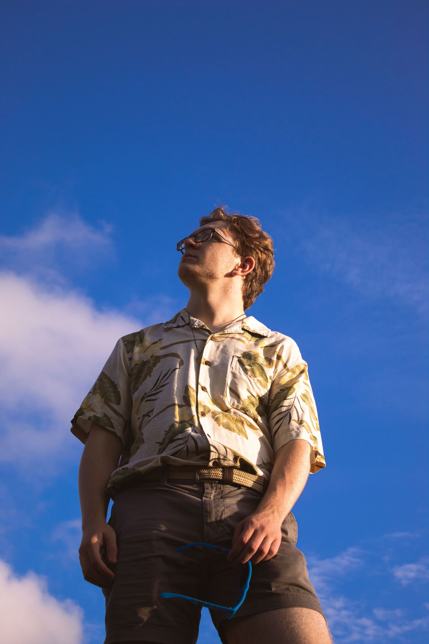 A man standing in front of a blue sky with clouds.