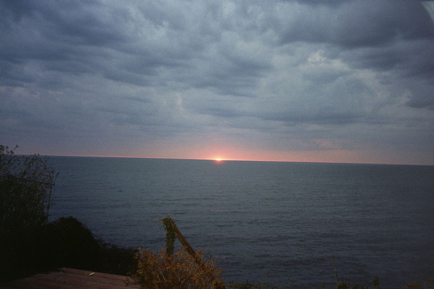 The sun setting on the horizon of a lake.