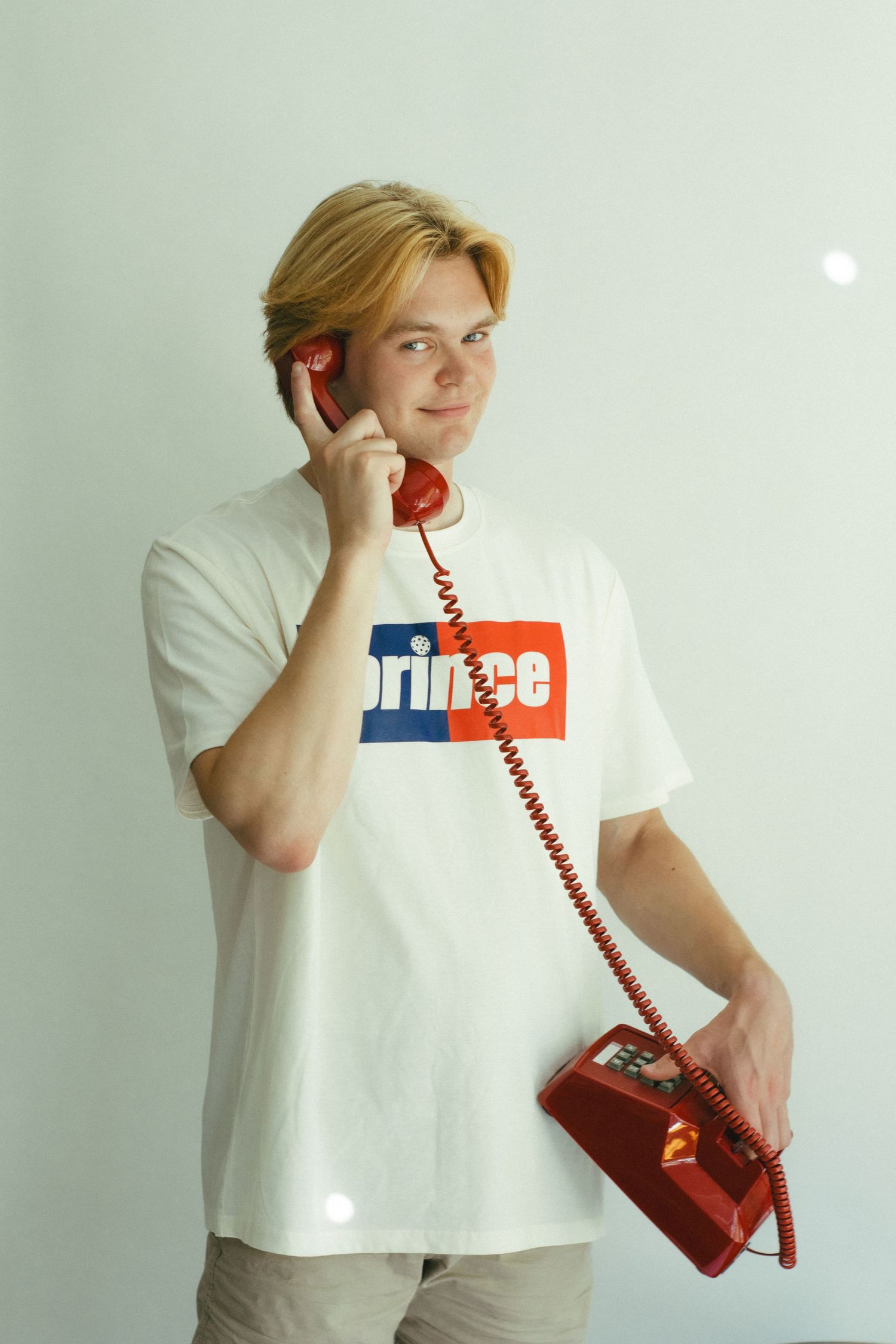 A man holding a red phone in front of a white background
