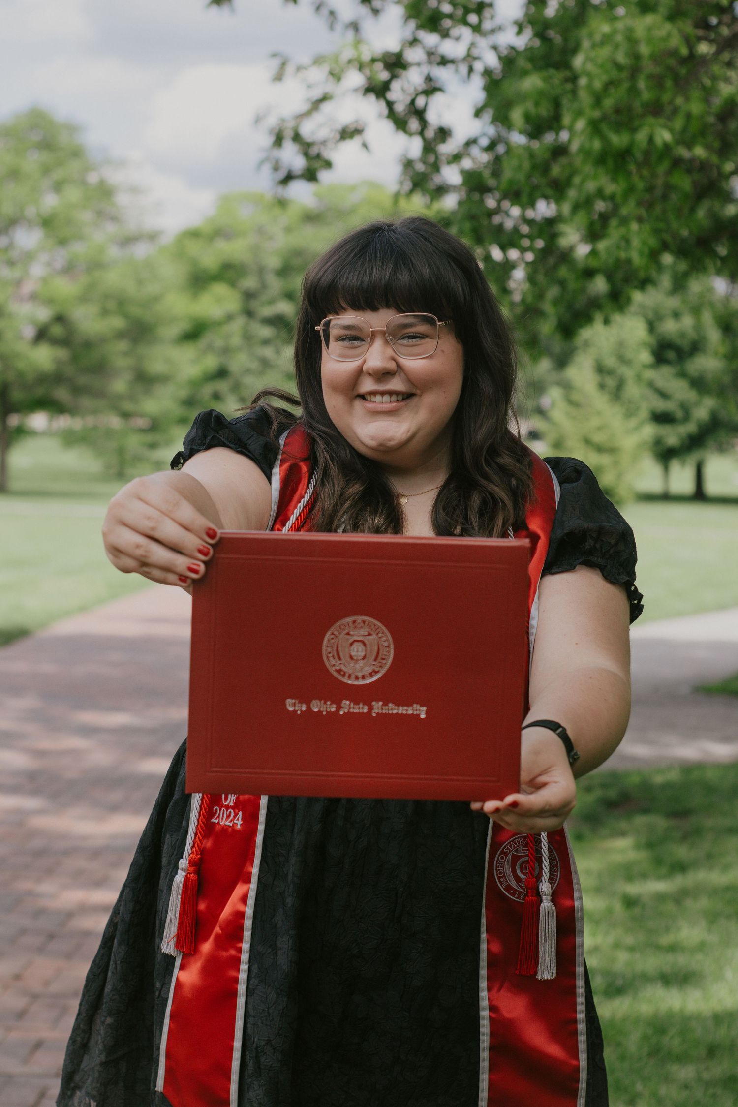 A woman holding her diploma to the camera