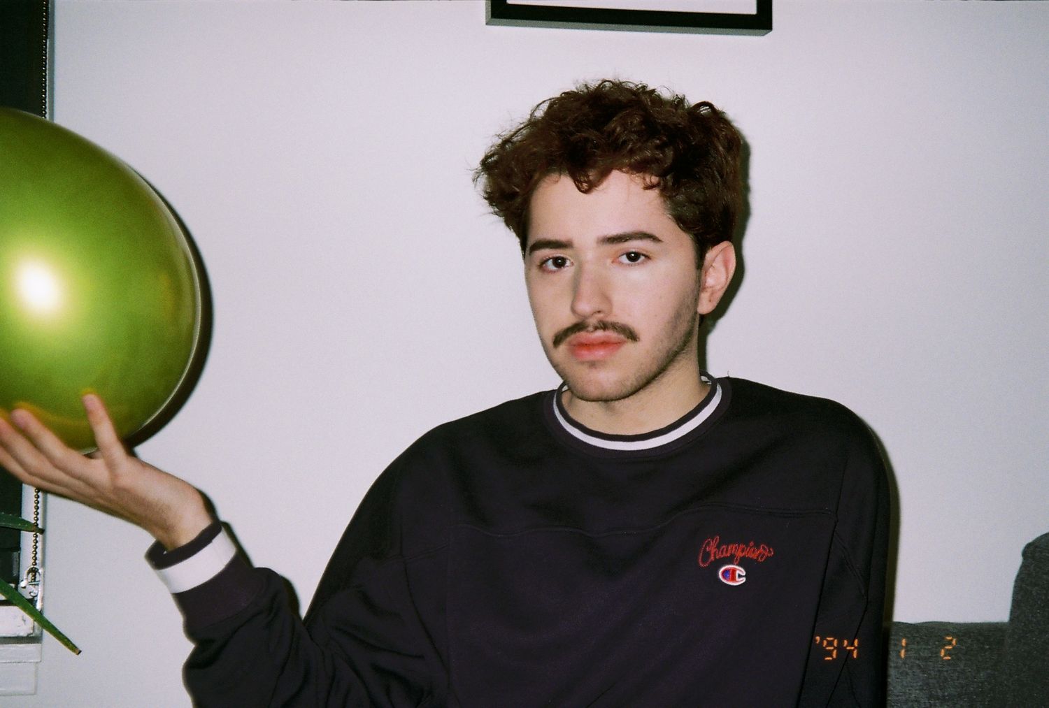 A film photograph of a young man holding a gold-colored balloon.