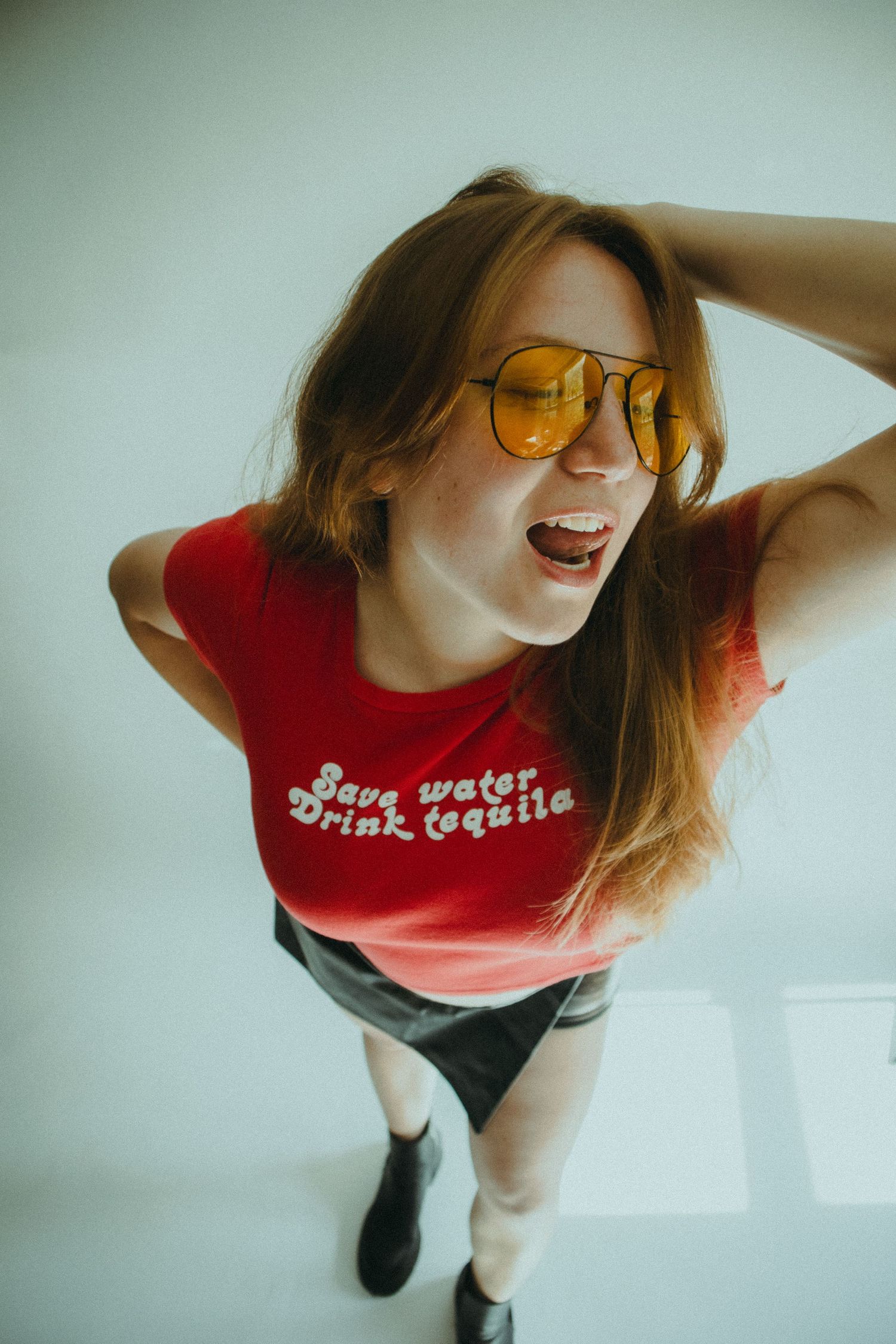 A fish-eye photo of a woman wearing yellow sunglasses looking at the camera.