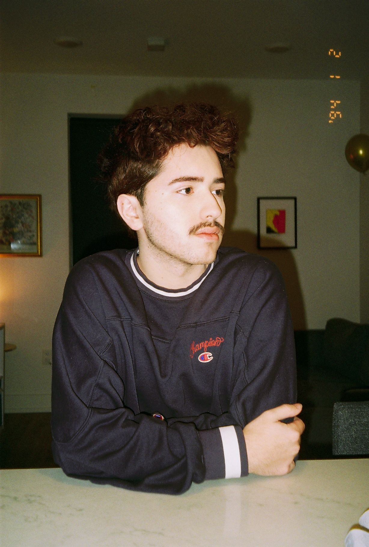 A young man in a blue sweater sitting at a counter.