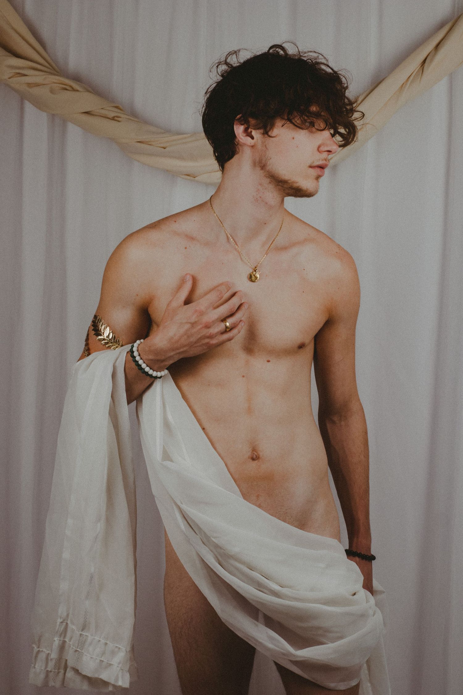 A photo of a man standing in front of a white curtain backdrop looking towards the right.