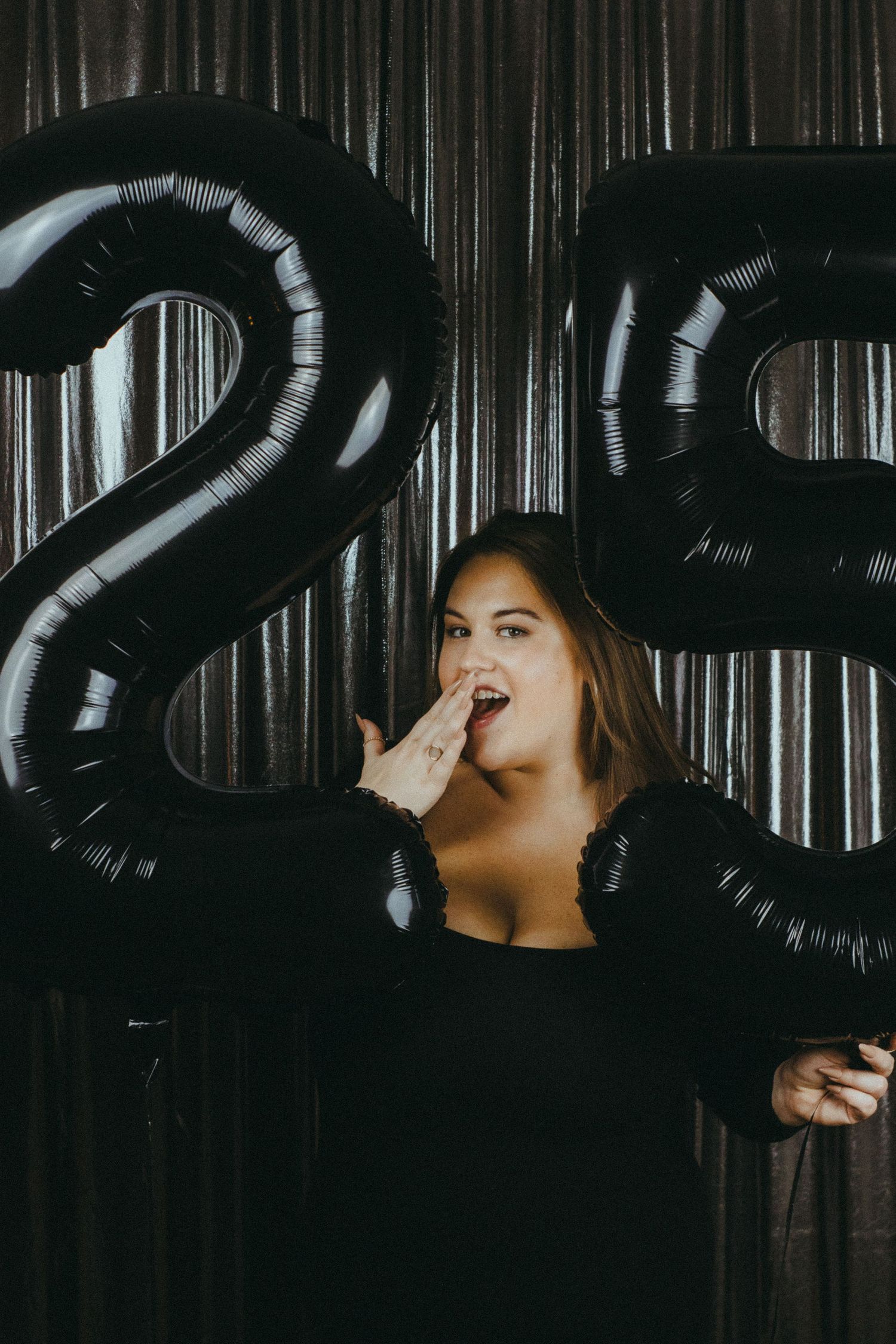 A woman posing between two balloons.