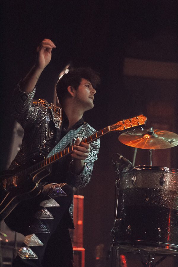 A man playing guitar near a drumset