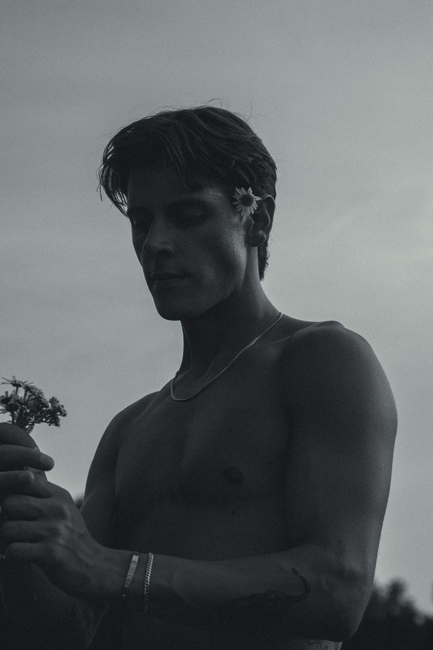 A black and white photo of a man looking at a small bouquet.