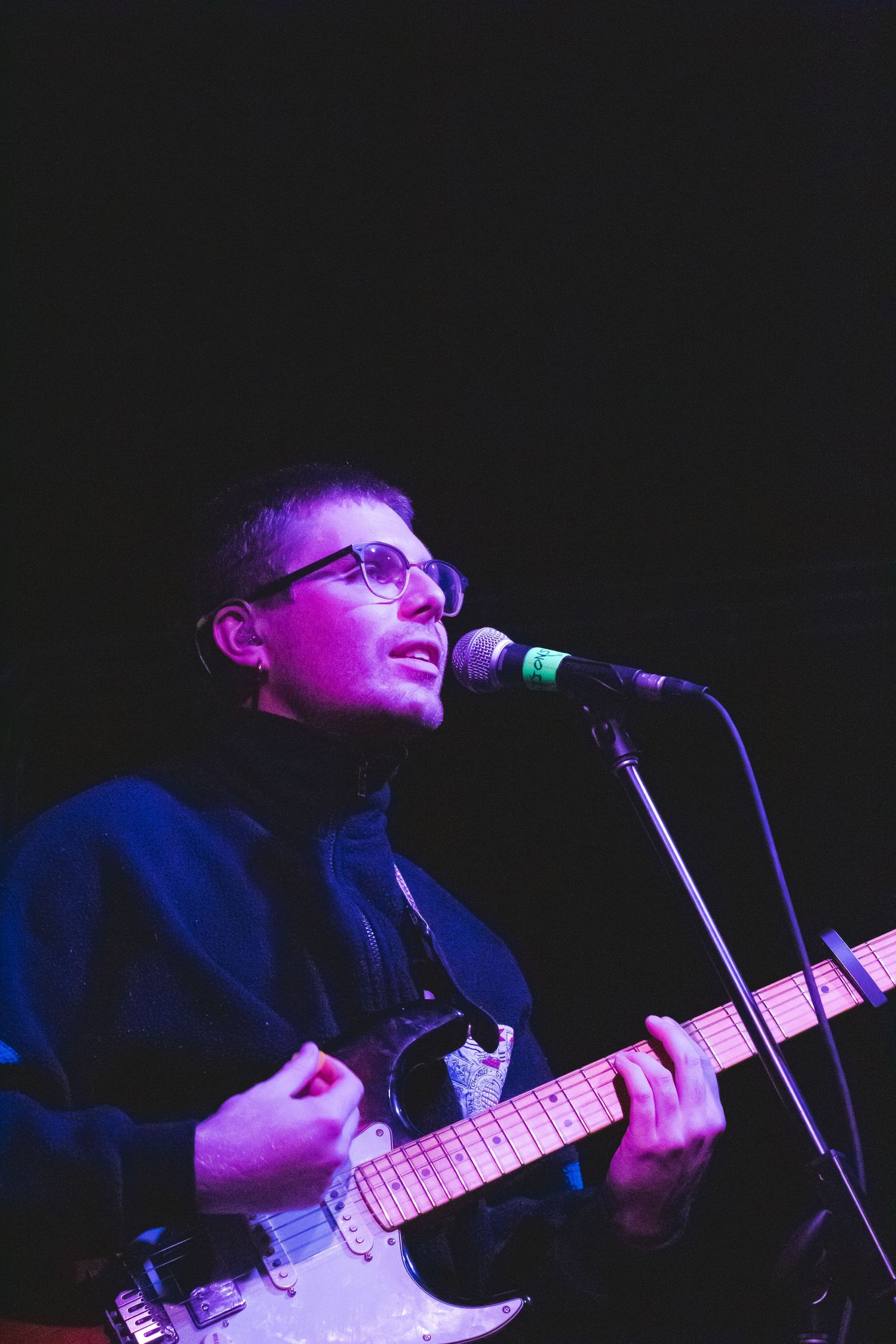 A man playing guitar and singing into a microphone