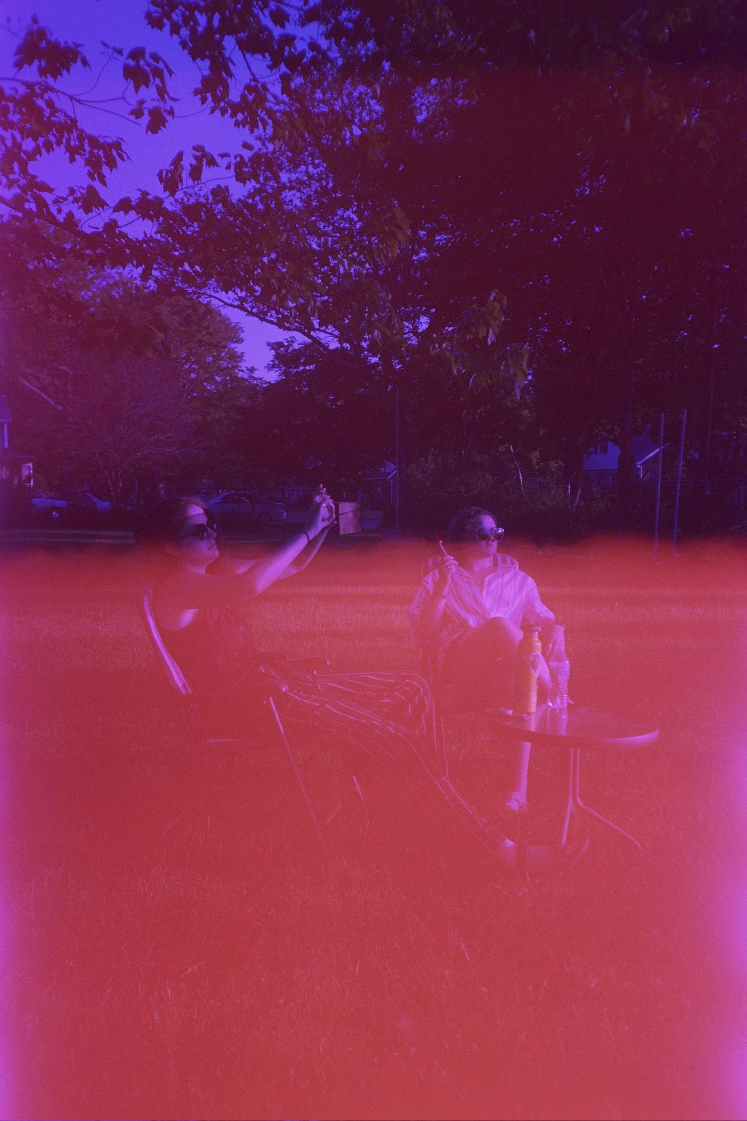 Two women sitting in lawn chairs underneath trees