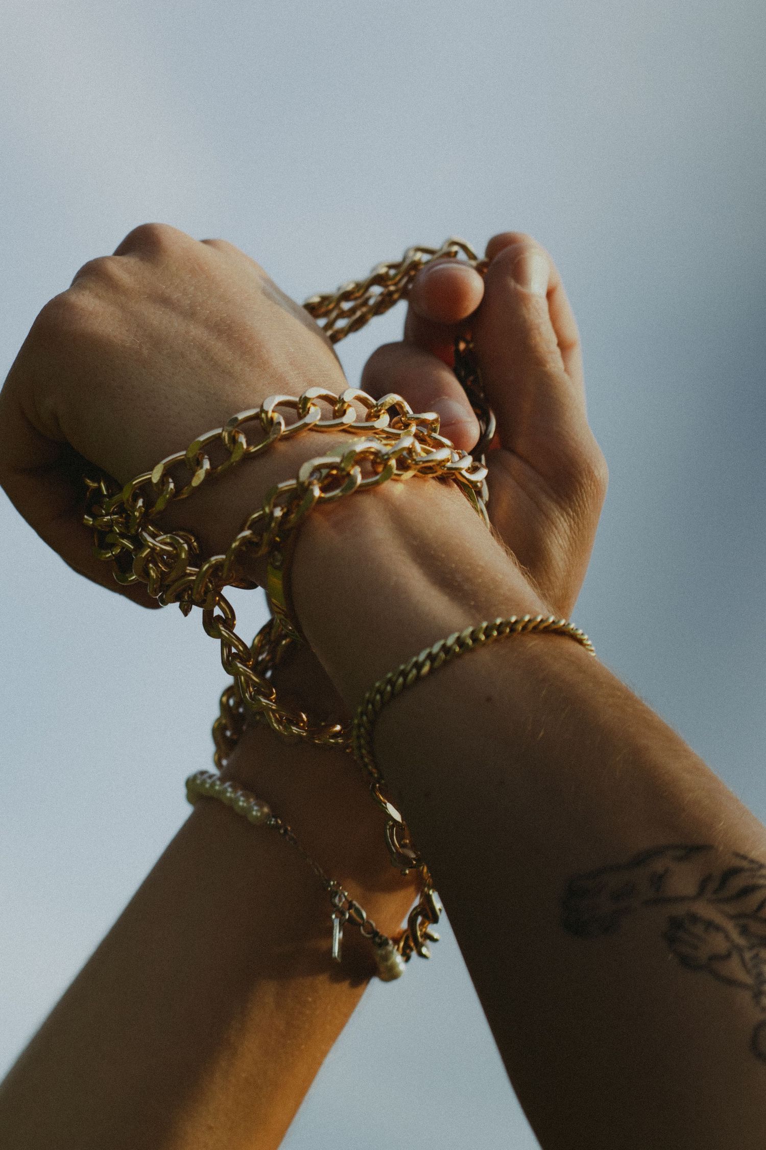 Two hands tied together with a golden chain.