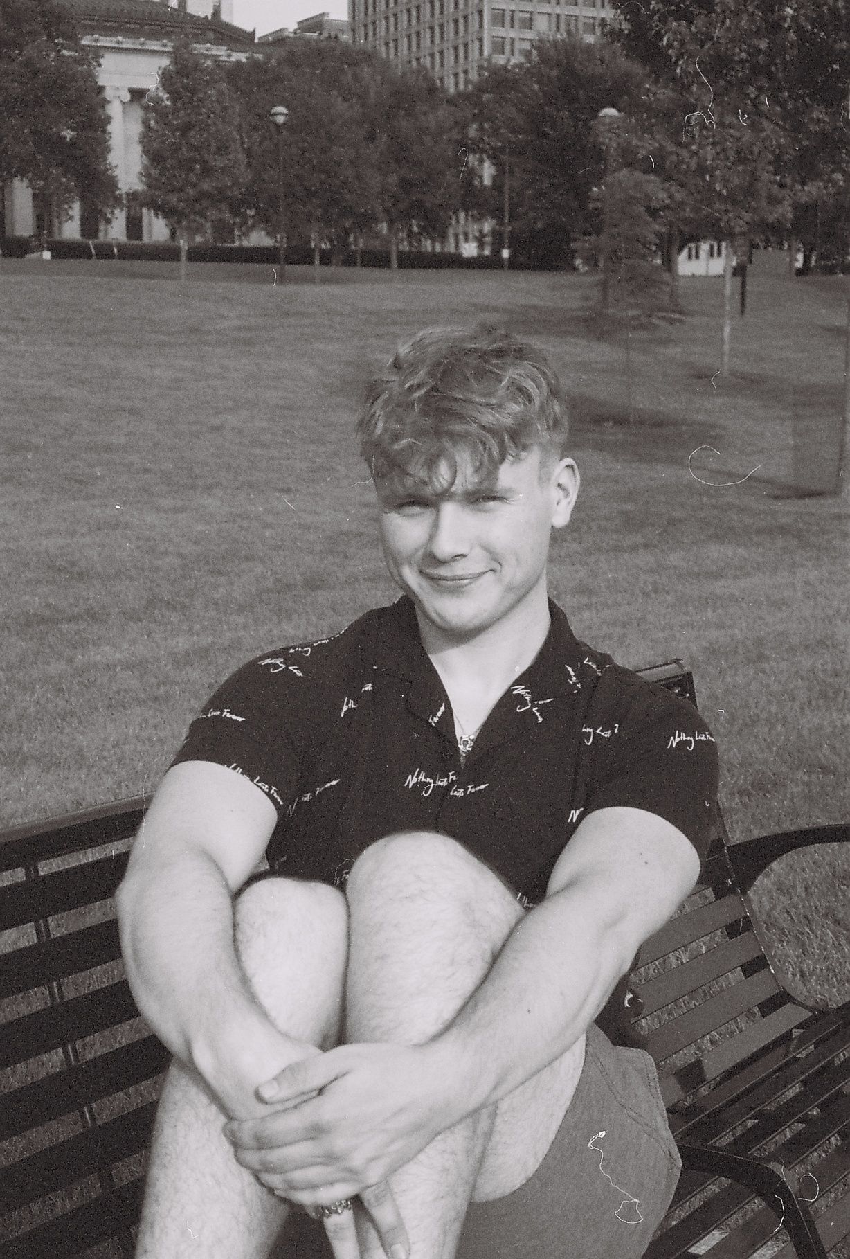 A man sitting on a bench, the photo is black and white.