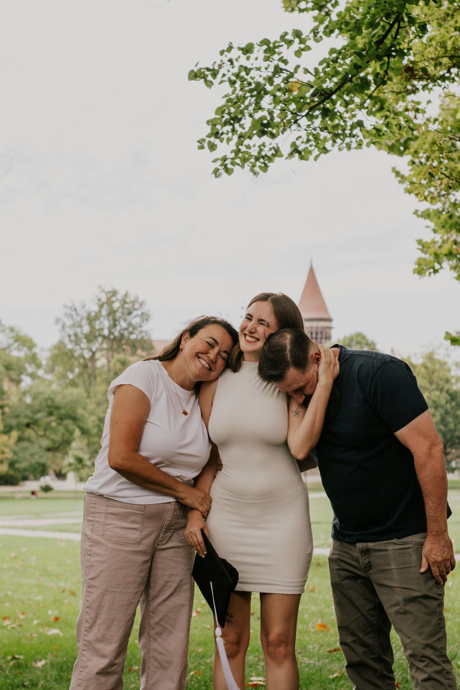 three people embracing in front of a grassy area