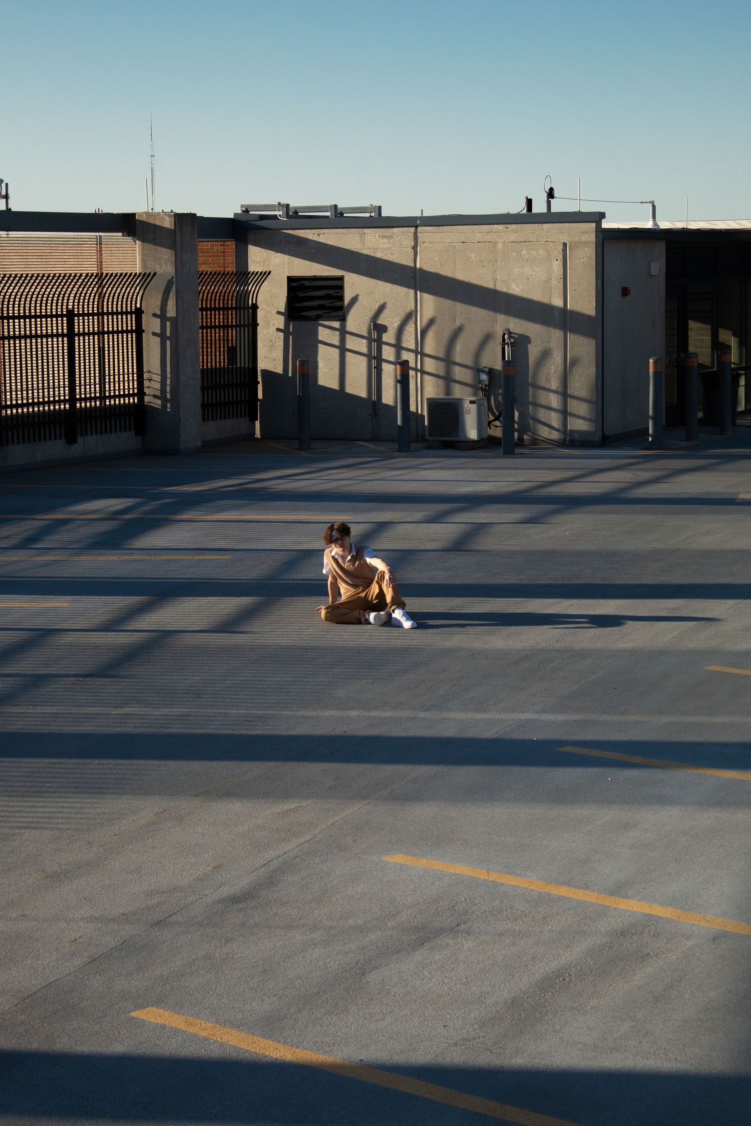 A man sitting on the concrete in a parking garage.