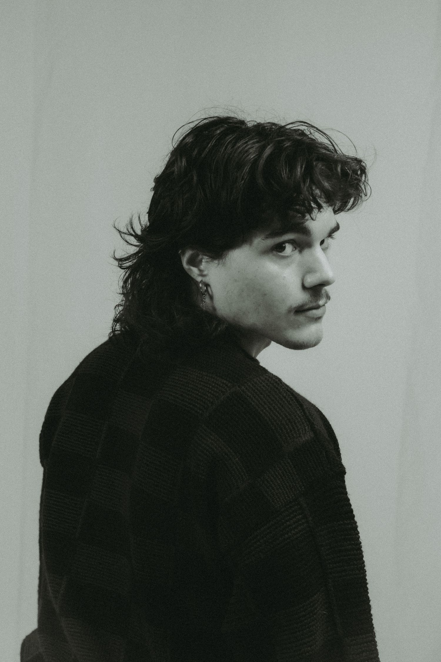 A man looking back at the camera in front of a white background.