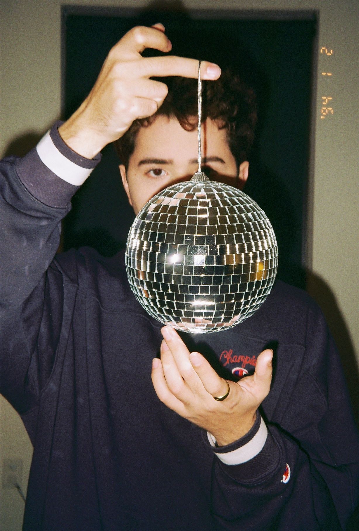 A film photograph of a man holding a small disco ball.