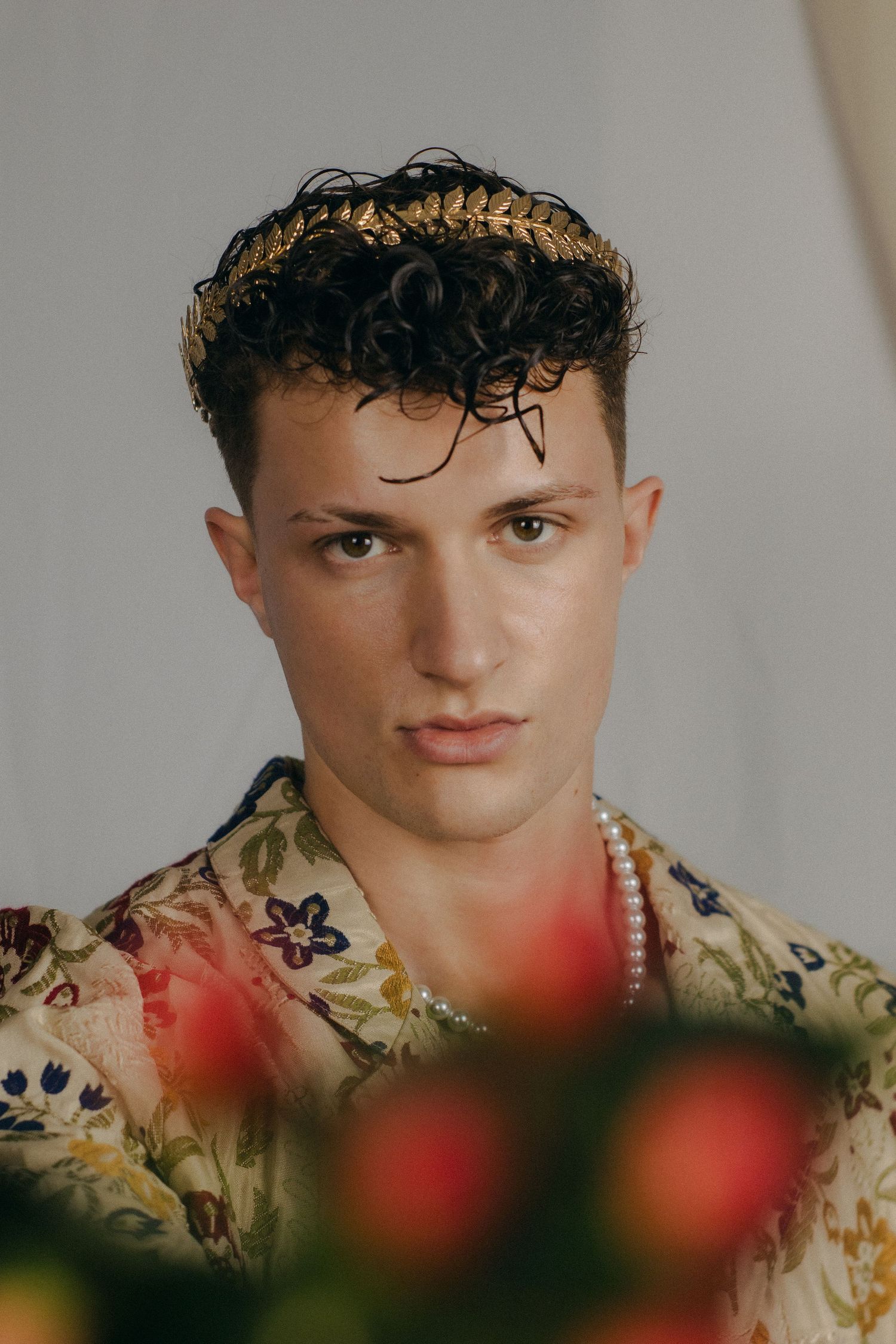 A man holding red flowers in front of a white background.
