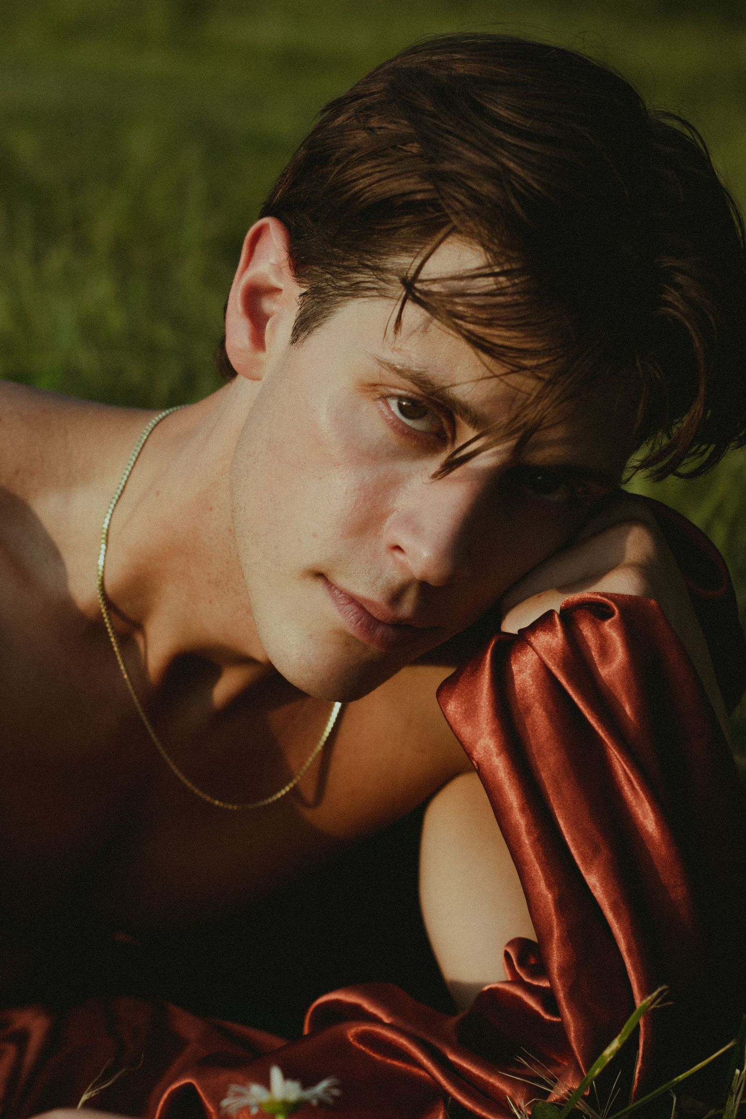 A man laying in a field looking towards the camera.