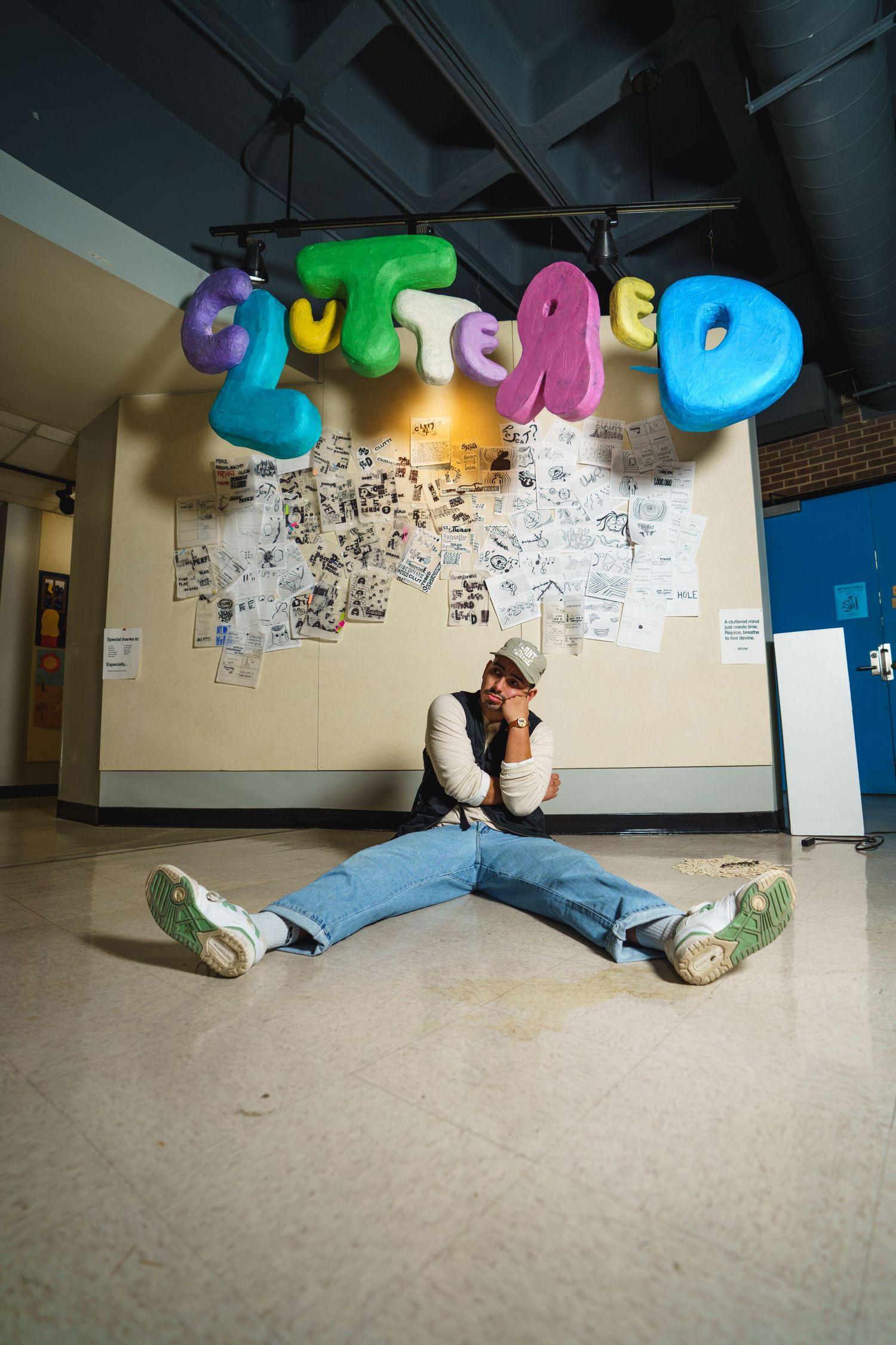 Person sits on floor beneath vibrant balloon letters and wall art in an indoor space.