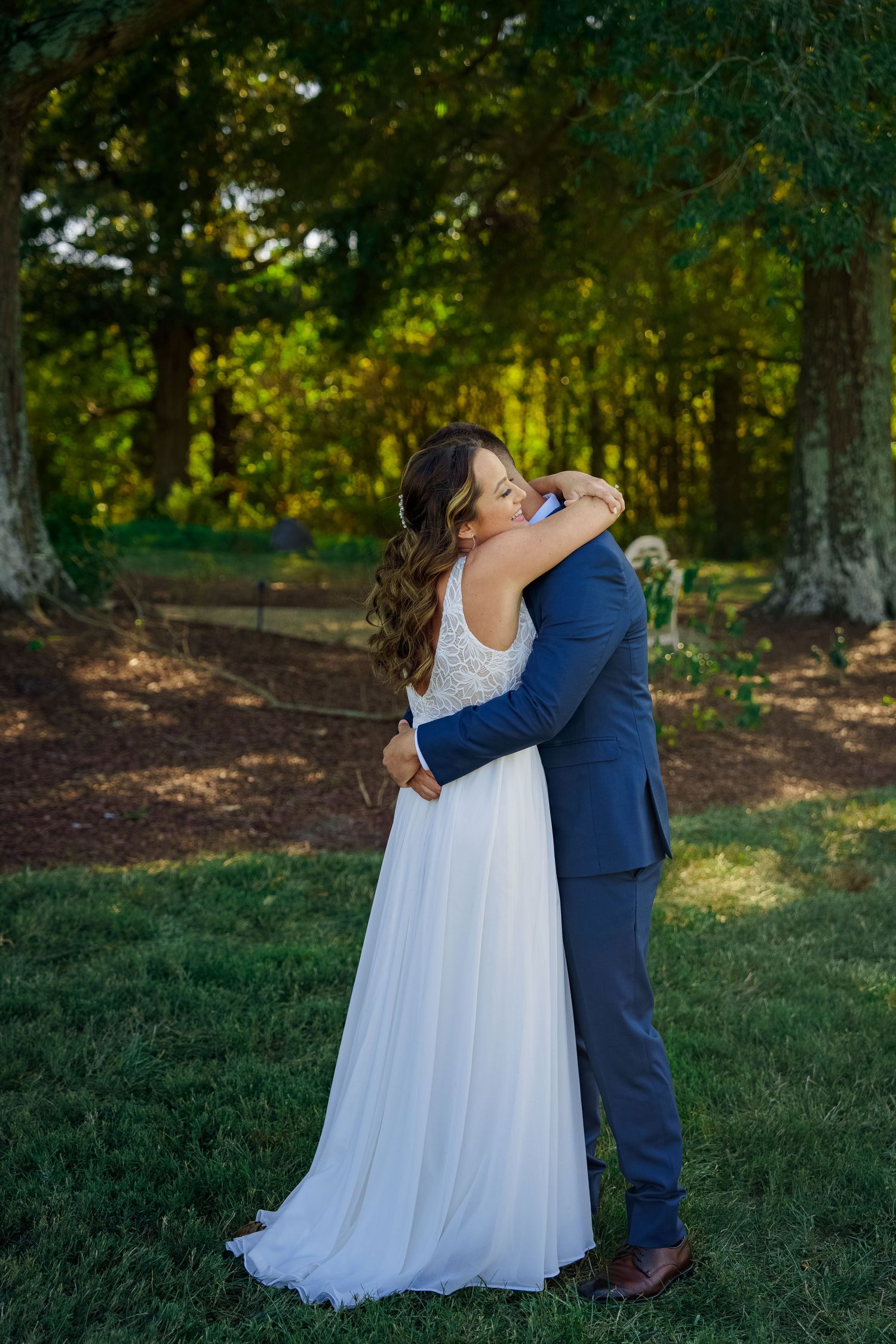 A romantic embrace between newlyweds surrounded by lush forest greenery.